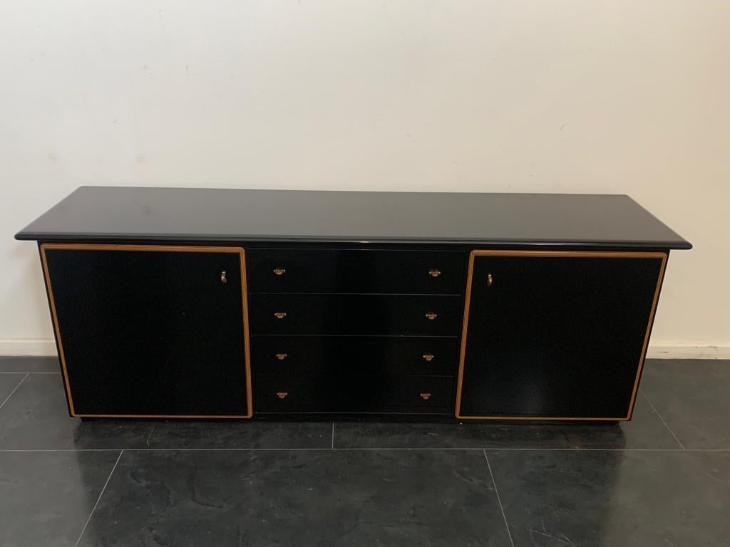 Roche Bobois production. Elegant black lacquered sideboard with profiles in two layers of wood and handles in metal and maple. It shows some signs of wear and tear due to age and use, see photo, on the top there are extensive micro scratches not
