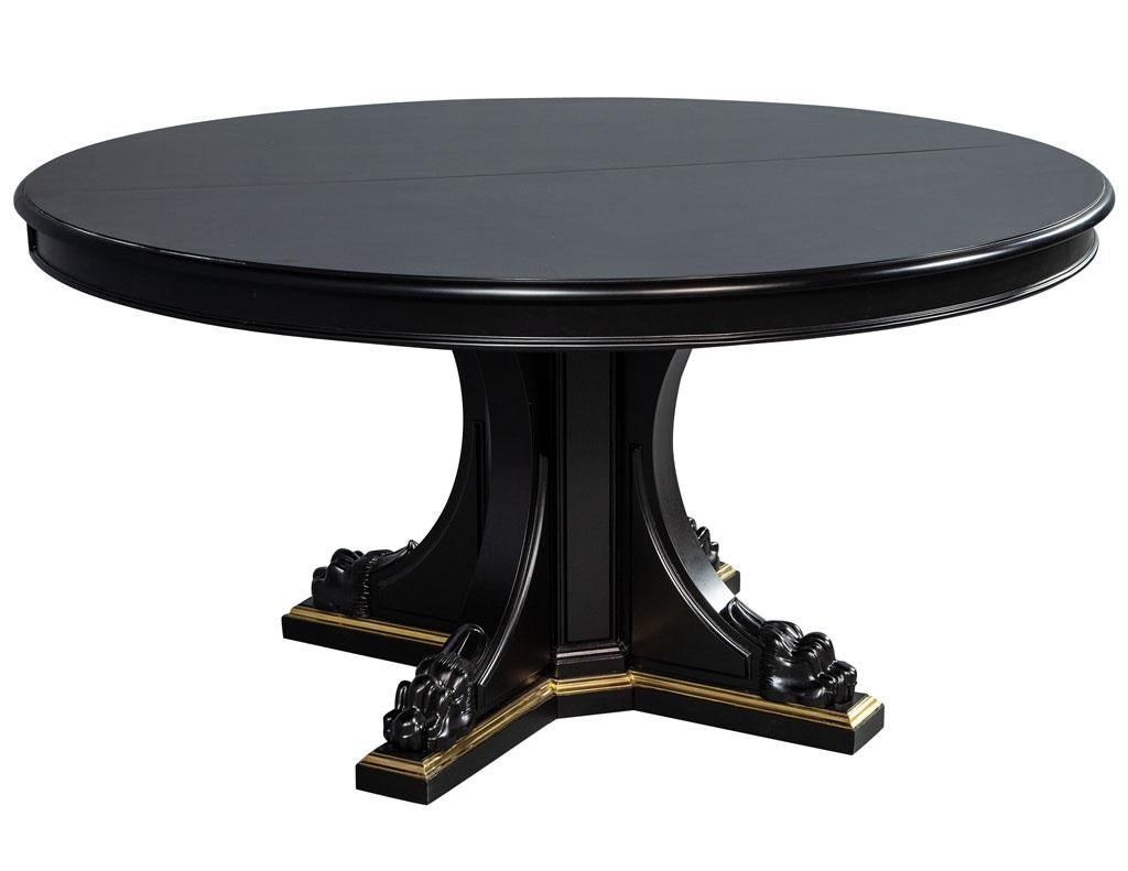 Designed with a modern flair of the empire style this table has a black ebony with a hand rubbed finish on mahogany. Finely detailed with intricate carving and a solid brass trim on the base. 

This table is expandable. Includes one extension leaf