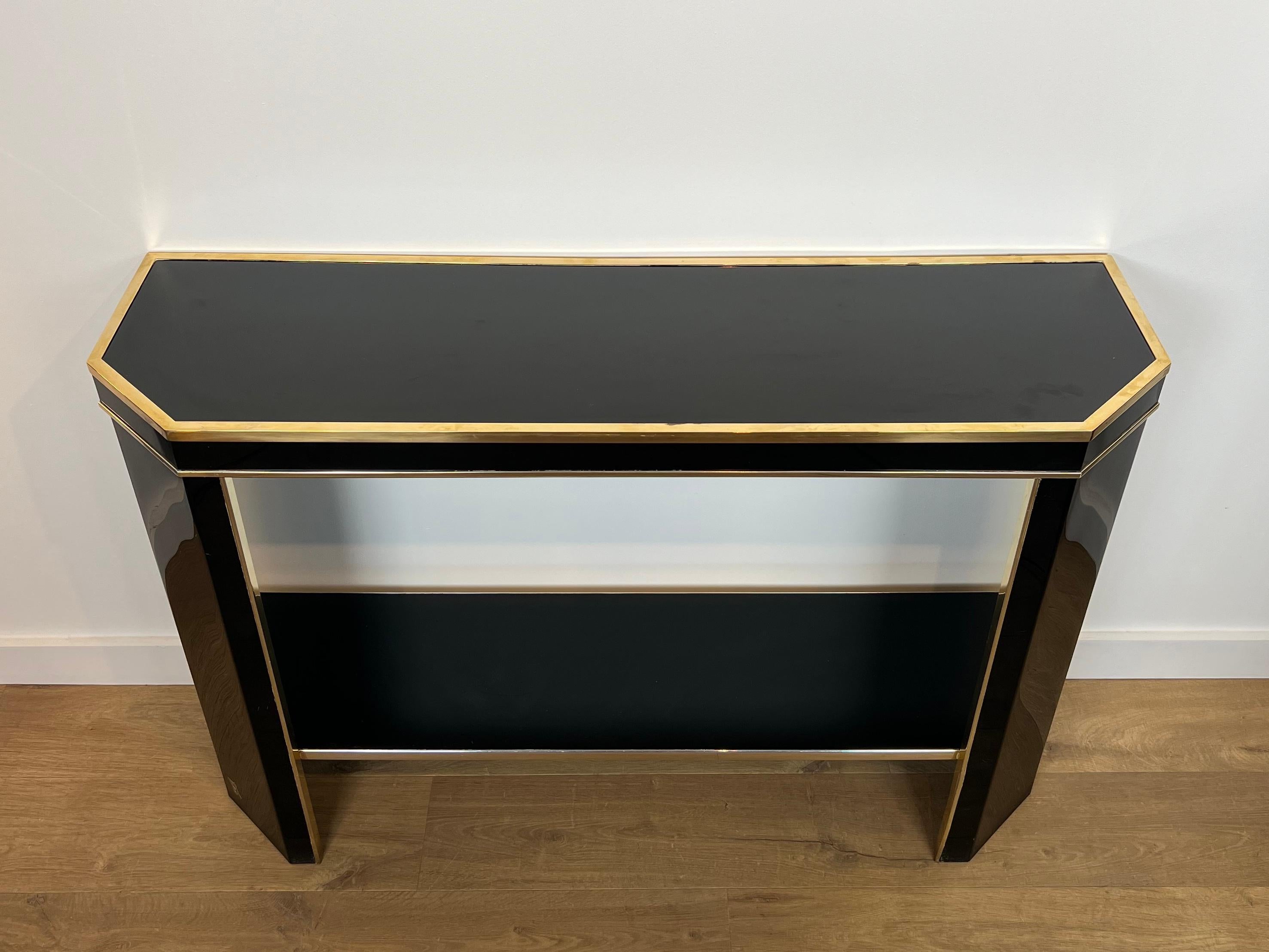Esta consola tan bonita es de madera lacada en negro y metal dorado. Se trata de una obra francesa firmada Jean Claude Mahey. Alrededor de 1970
