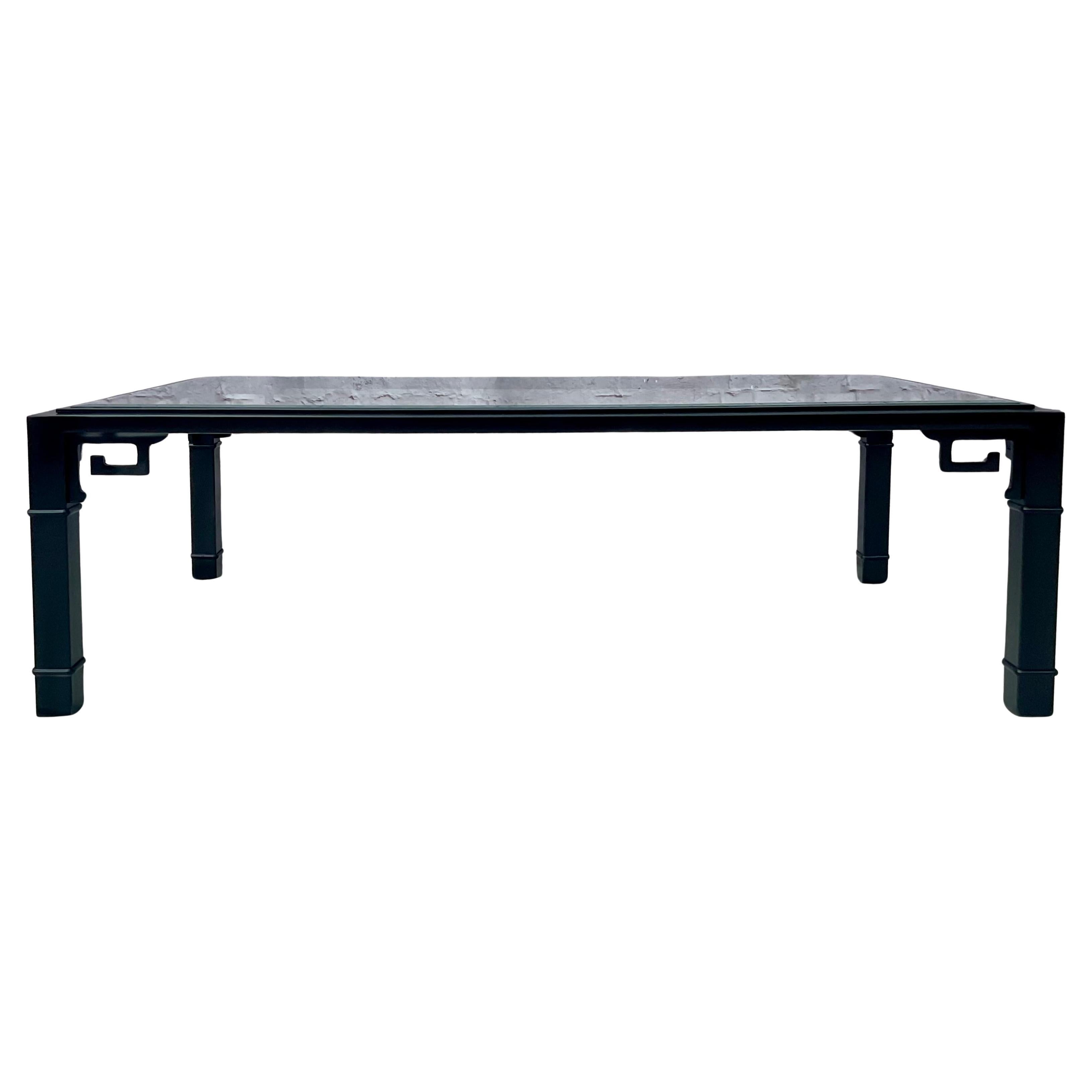 Table basse rectangulaire en fer laqué noir avec plateau en verre. La table se caractérise par des consoles à frettes en forme de clé grecque  sous les angles du plateau, ce qui ajoute à la fois un intérêt visuel et un caractère structurel. Le