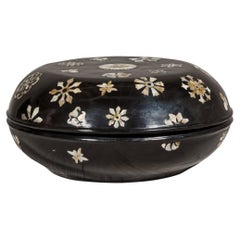 Boîte circulaire à couvercle laqué noir avec décor floral en nacre