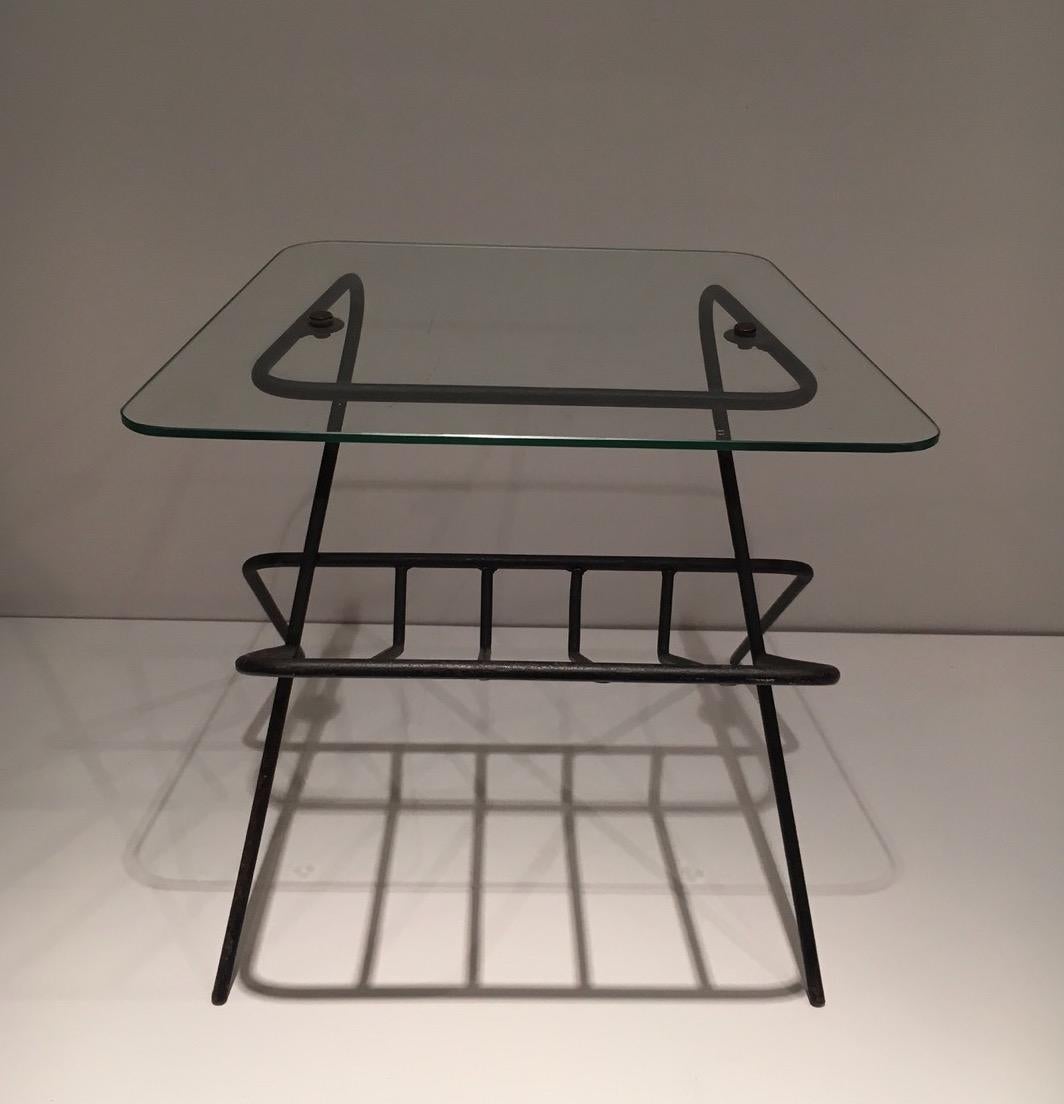 This magazine rack is made of black lacquered metal and glass shelf. This is a French work. Circa 1950