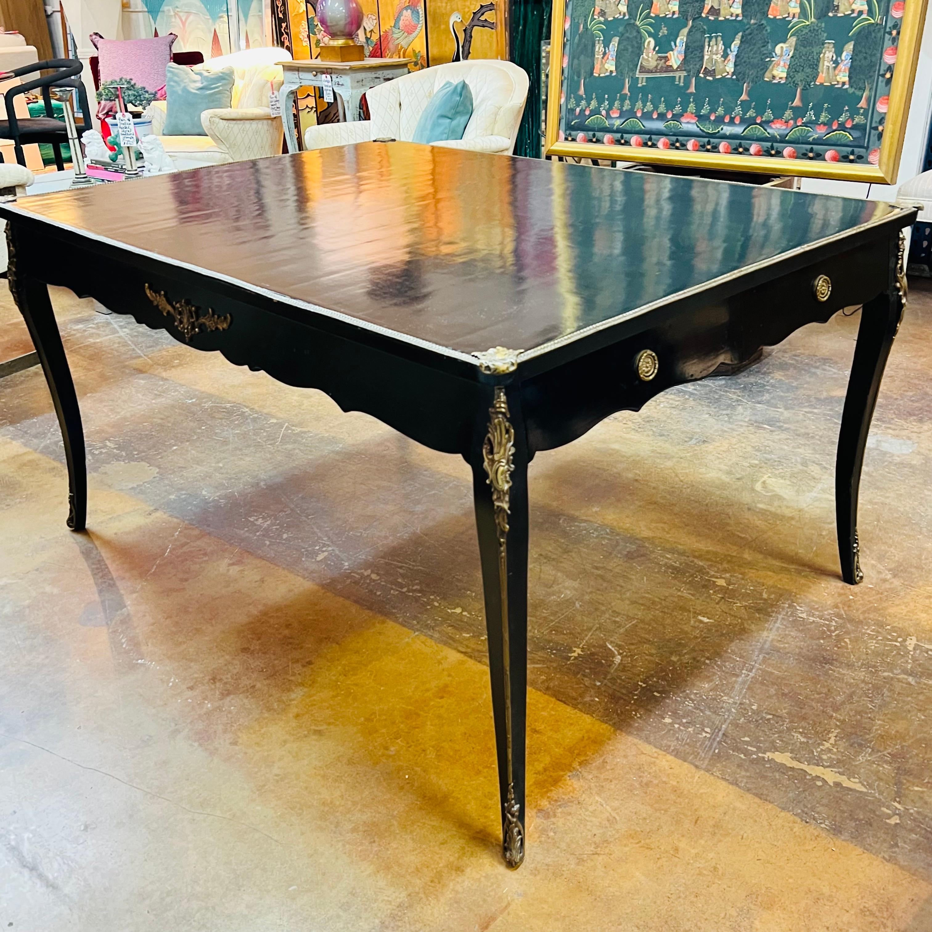 French Louis XV writing desk featuring cabriole legs, exquisite ormolu, and a glossy black lacquered top. The elegant gilt bronze fittings protect the edges and at the same time accentuate them. The table has two drawers at each side. Previously