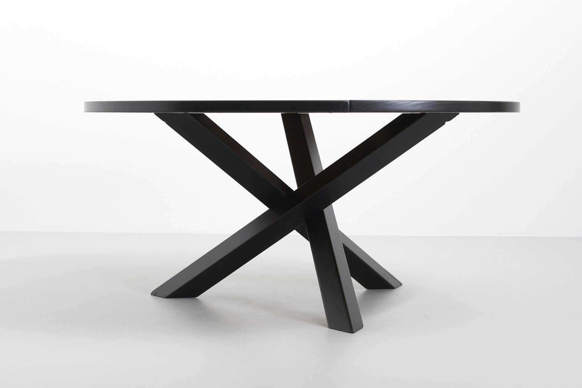 A large round dining table in black lacquered ash, designed by Martin Visser for 't Spectrum, the Netherlands, 1960s. The round top is divided into three parts. The base consist of three crossed legs of solid wood.