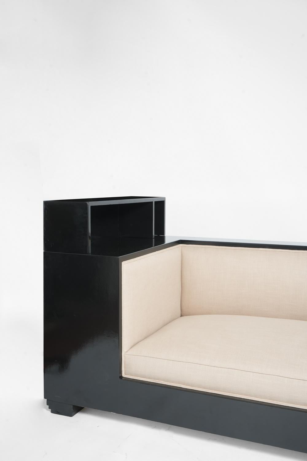 Sofa with full cheeks in black lacquered wood, wide armrests and resting on small stepped feet enhanced by plinth feet. in the style of Djo Bourgeois. France, 1930s.