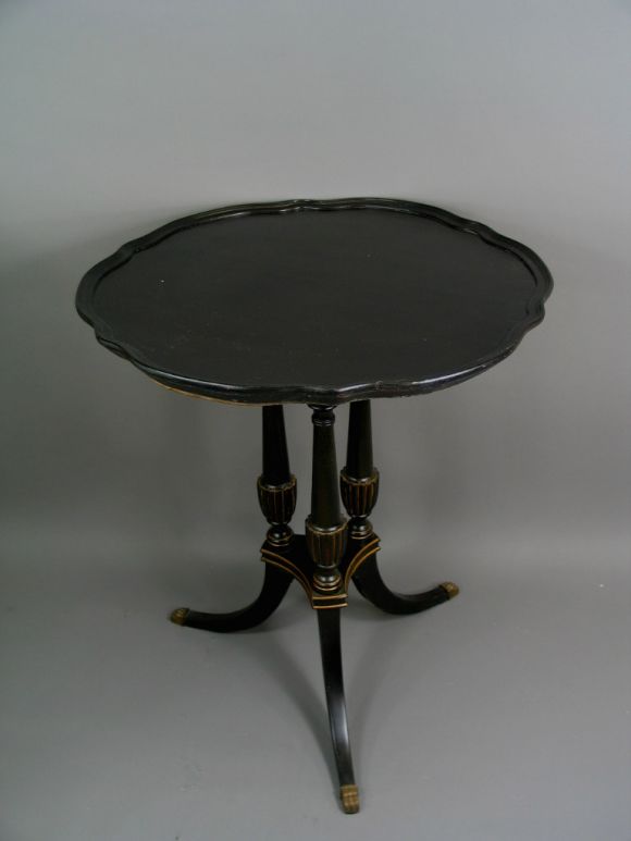 Black lacquered and gilded wood table with triple columns base with pie-crust top and brass.