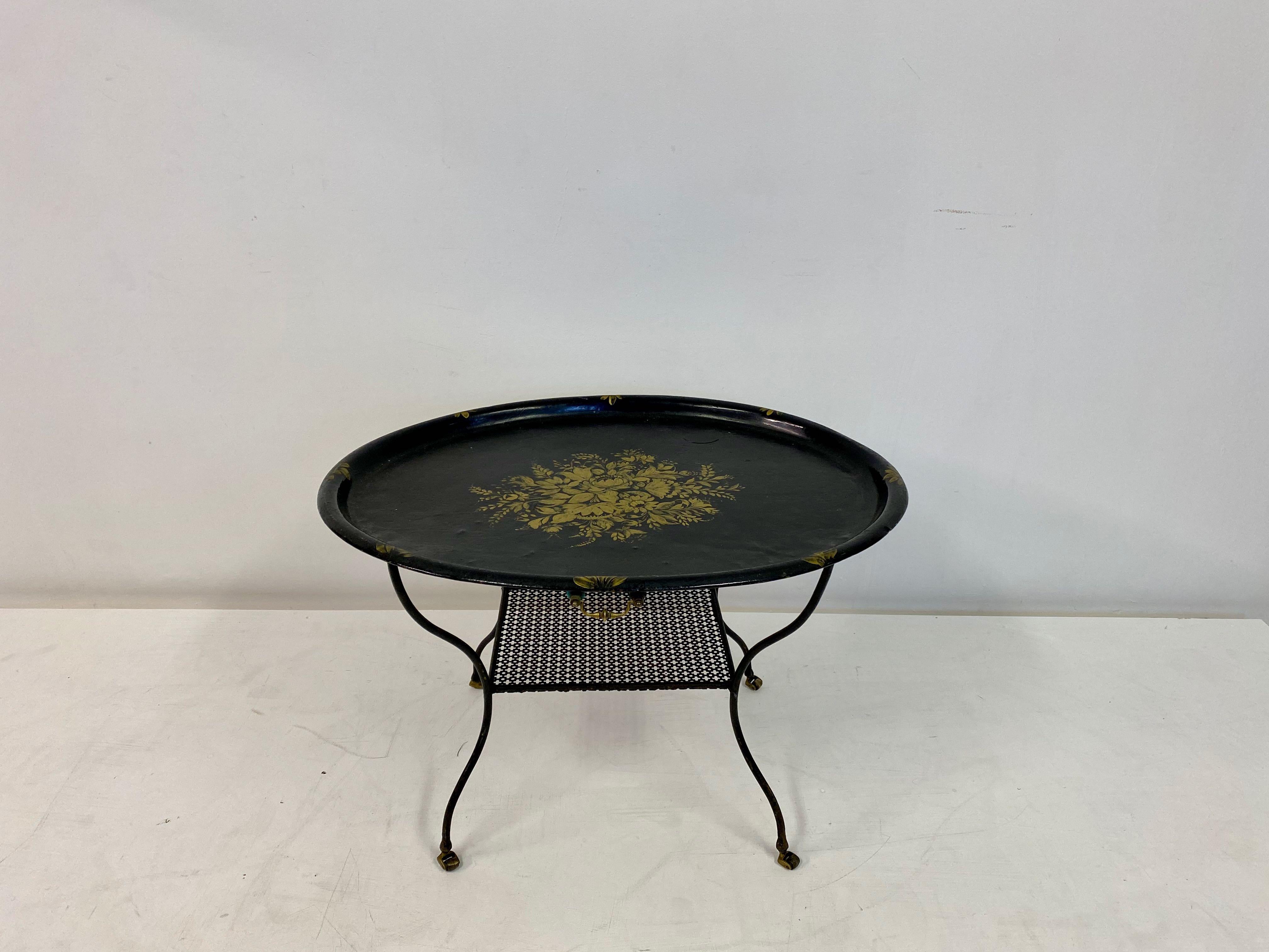 Tray table

Black lacquered tray

Flower decoration

Black metal stand on brass castors

Perforated metal shelf

French early 20th century.