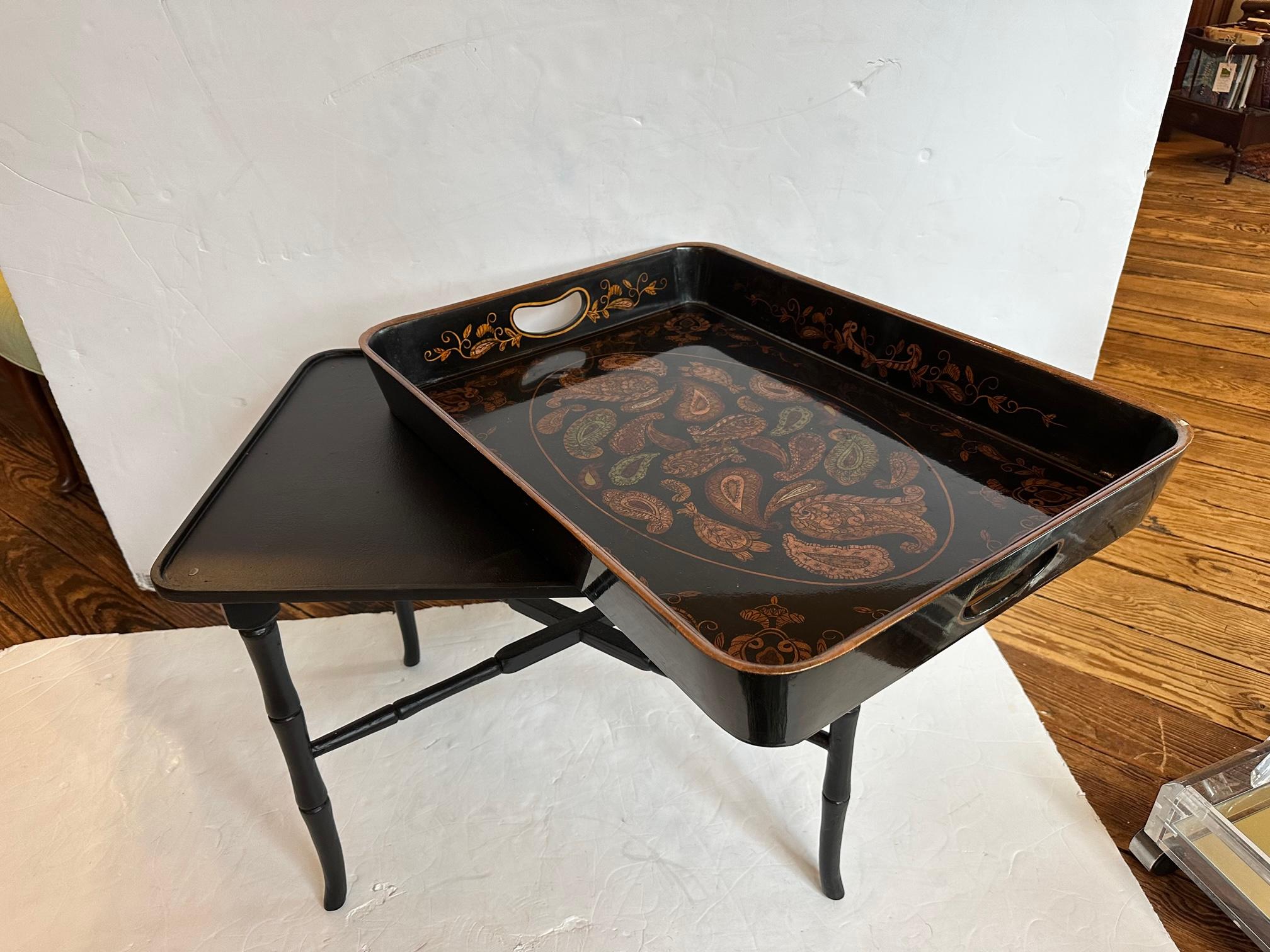 Black lacquer tray with paisley design in gold, probably from late 80's/early 90's, sitting on a delicate bamboo style ebonized stand which has been recently repainted in satin black. A recent touchup to a small chip in lacquered top is visible. 