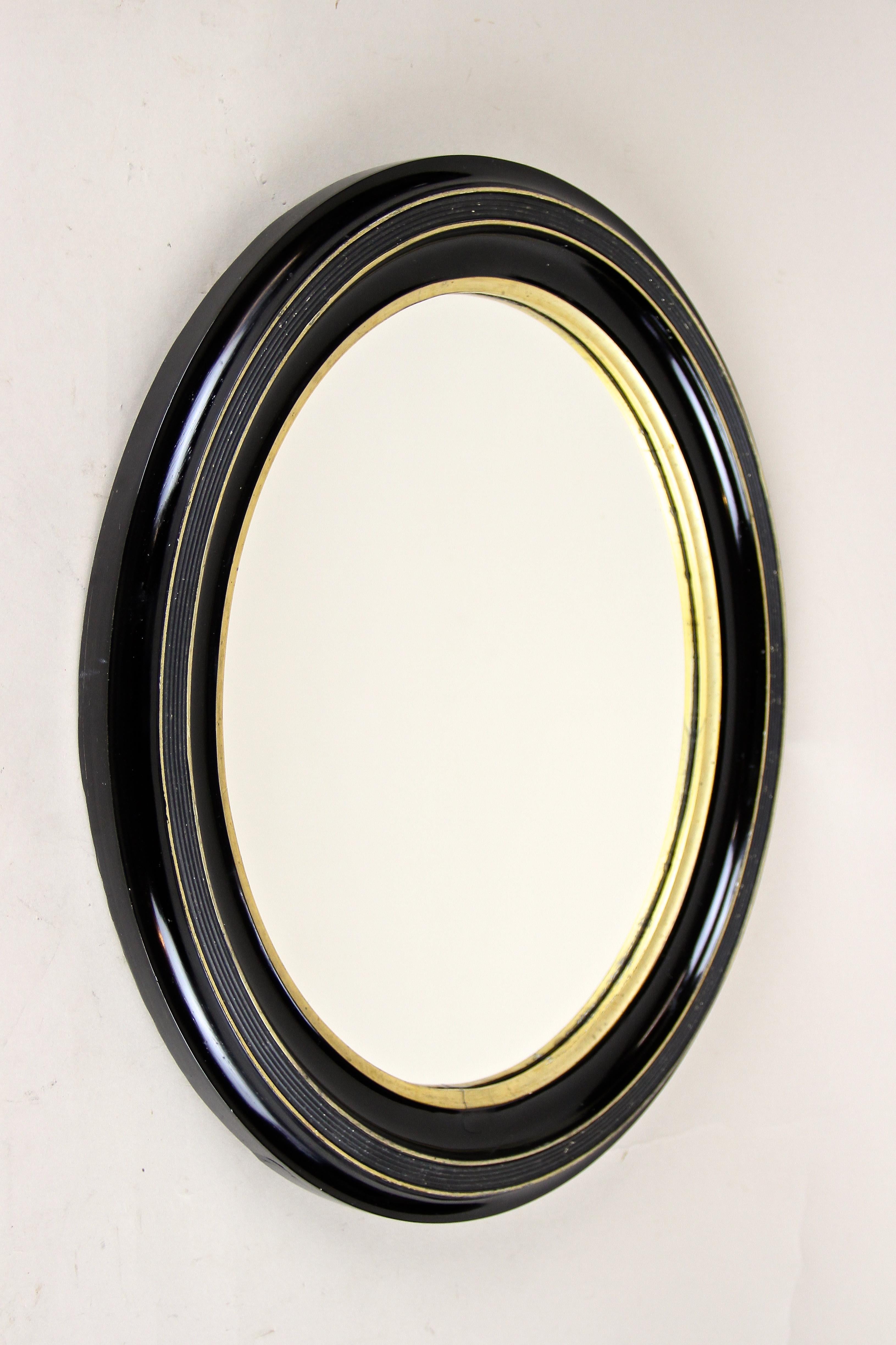 Stunning oval Art Nouveau wall mirror artfully processed in Vienna/ Austria at the beginning of the 20th century. The slightly grooved solid wooden oval frame from circa 1900 shows a black lacquered surface with an additional hand-polished shellac