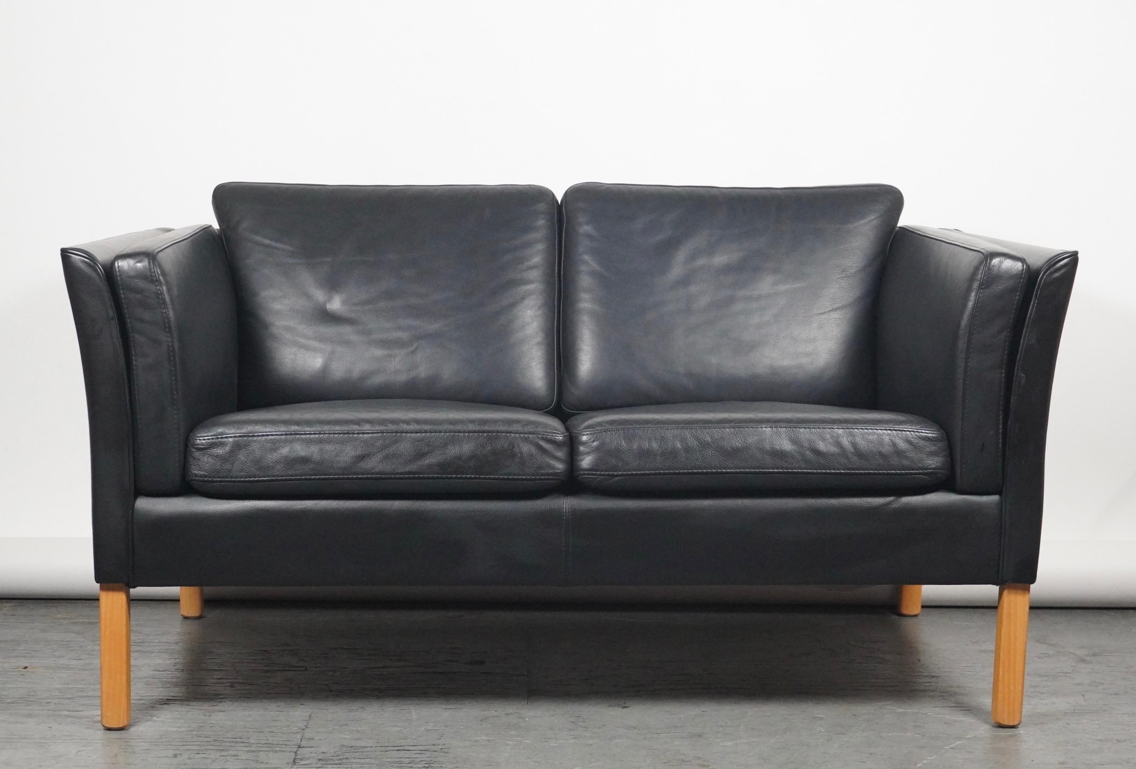 Black leather settee in the style of Borge Mogensen by Stouby of Denmark who are known for their quality made furniture and are considered second only to Fredericia, who produced the actual design. Gently curved arms with square beech legs and black