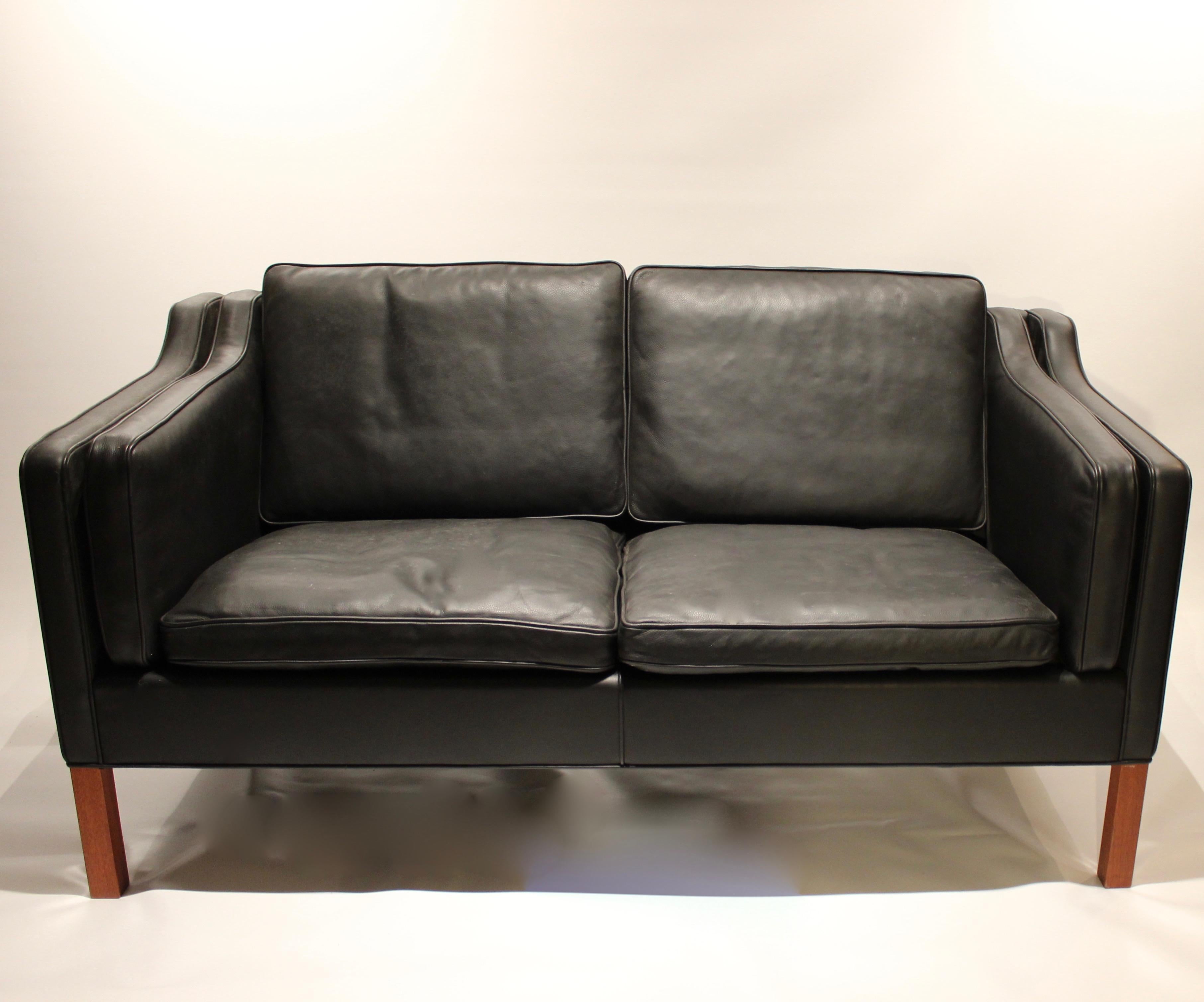 Black leather 2-seat sofa with legs of mahogany, model 2212, designed by Børge Mogensen in 1962 and manufactured by Fredericia furniture in the 1980s. The sofa is in great vintage condition and we currently have two in stock.
