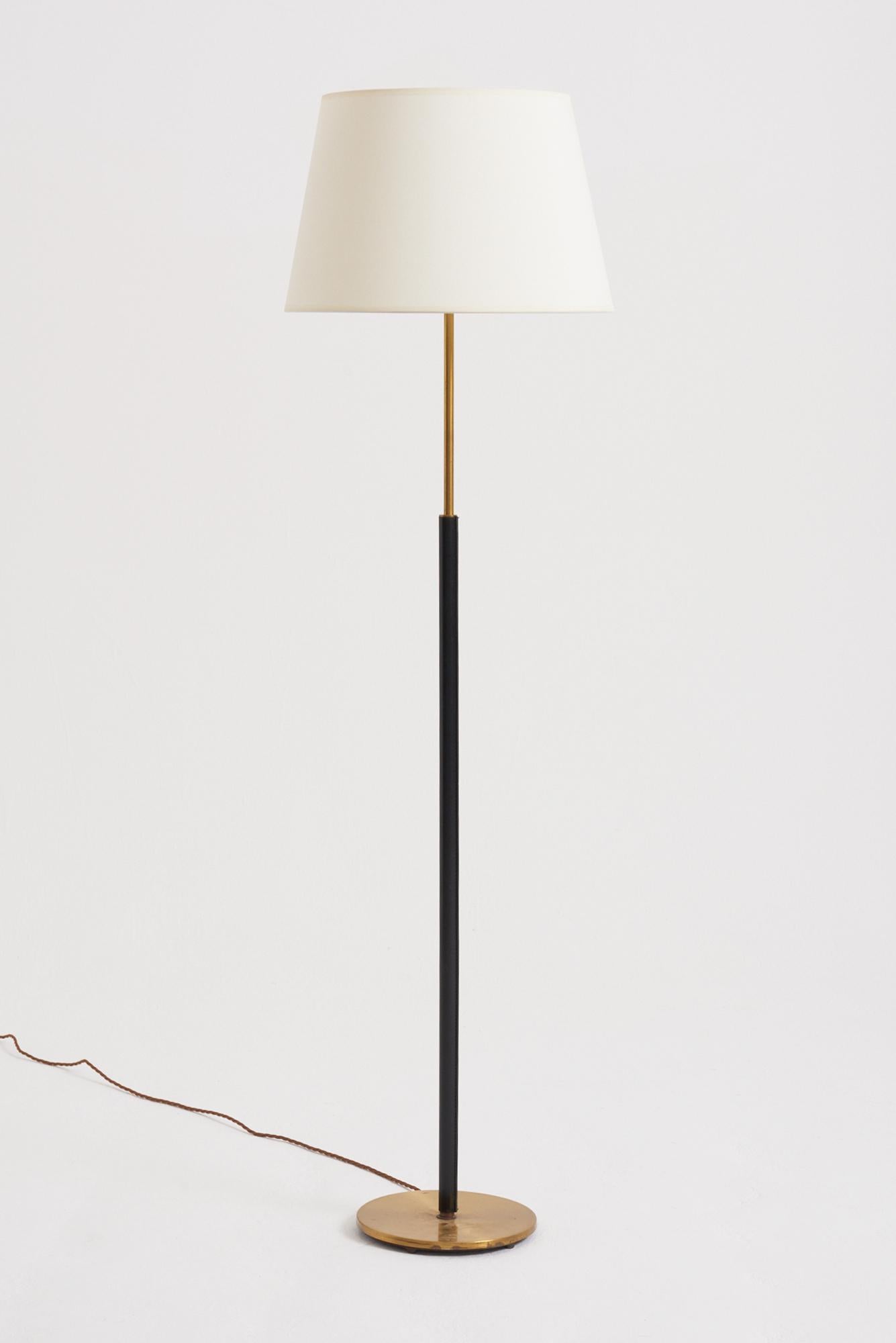 A brass and faux black leather floor lamp by Falkenbergs Belysning. 
Sweden, third quarter of the 20th Century
With the shade: 144 cm high by 41 cm diameter
Lamp base only: 126 cm high by 23 cm diameter