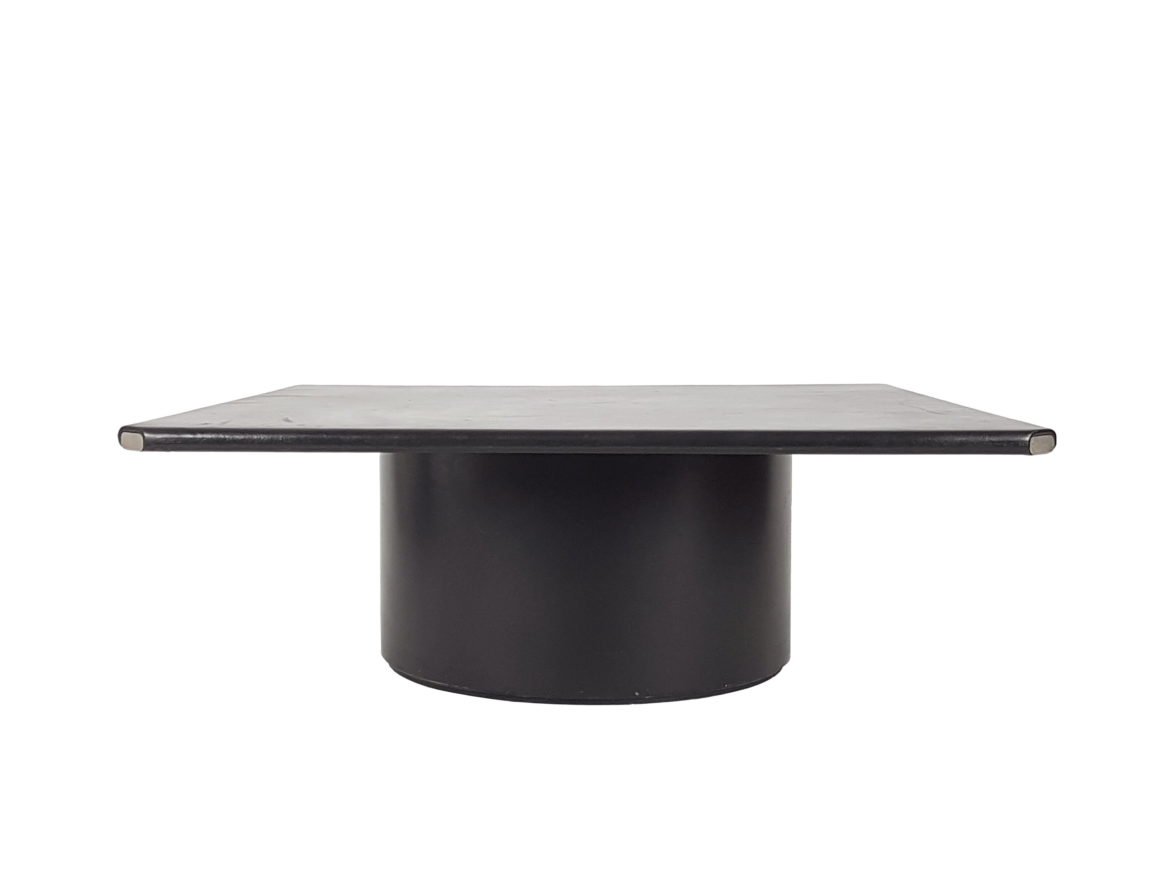 This rare side/coffee table was designed by Afra e Tobia Scarpa for B&B Italia in 1974. It is made from a cylindrical black fiberglass base with a coated black leather top. Each corner is finished with a nickel-plated metal plate as showed in