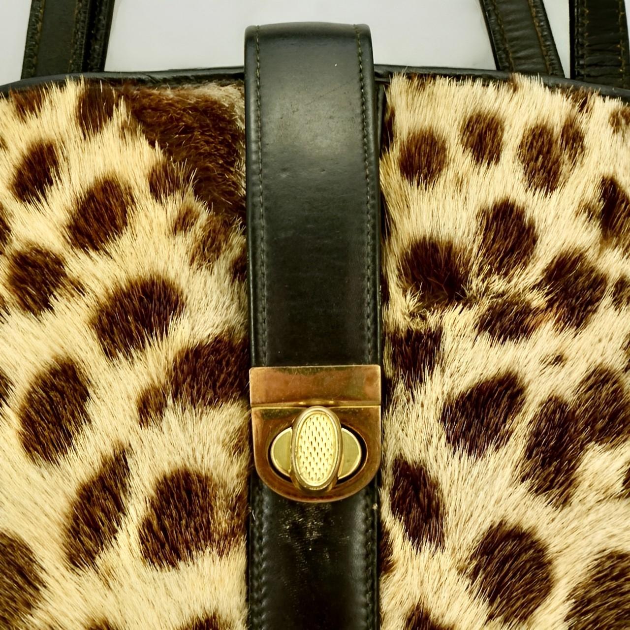 Fabuleux sac à main en cuir noir et fourrure tachetée (peut-être du poney), avec des accessoires plaqués or.

Il mesure 26,5 cm de large à la base, 23,4 cm de haut, environ 5,5 cm de profondeur et sa sangle tombe à 12,5 cm.

L'intérieur est doublé