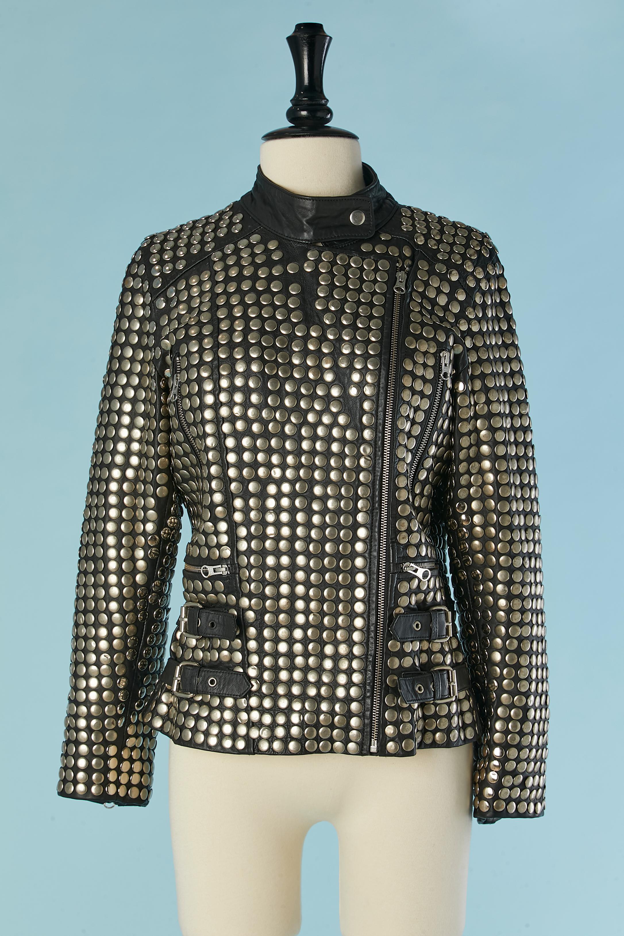 Schwarze Biker-Jacke aus Leder mit silbernen Metallnieten. Reißverschluss in der vorderen Mitte und an den Taschen. 2 Halbgürtel auf jeder Seite und Schnallen. Futter aus Wildlederimitat. Schnappverschluss am Kragen. 
SIZE XS auf dem Etikett, passt