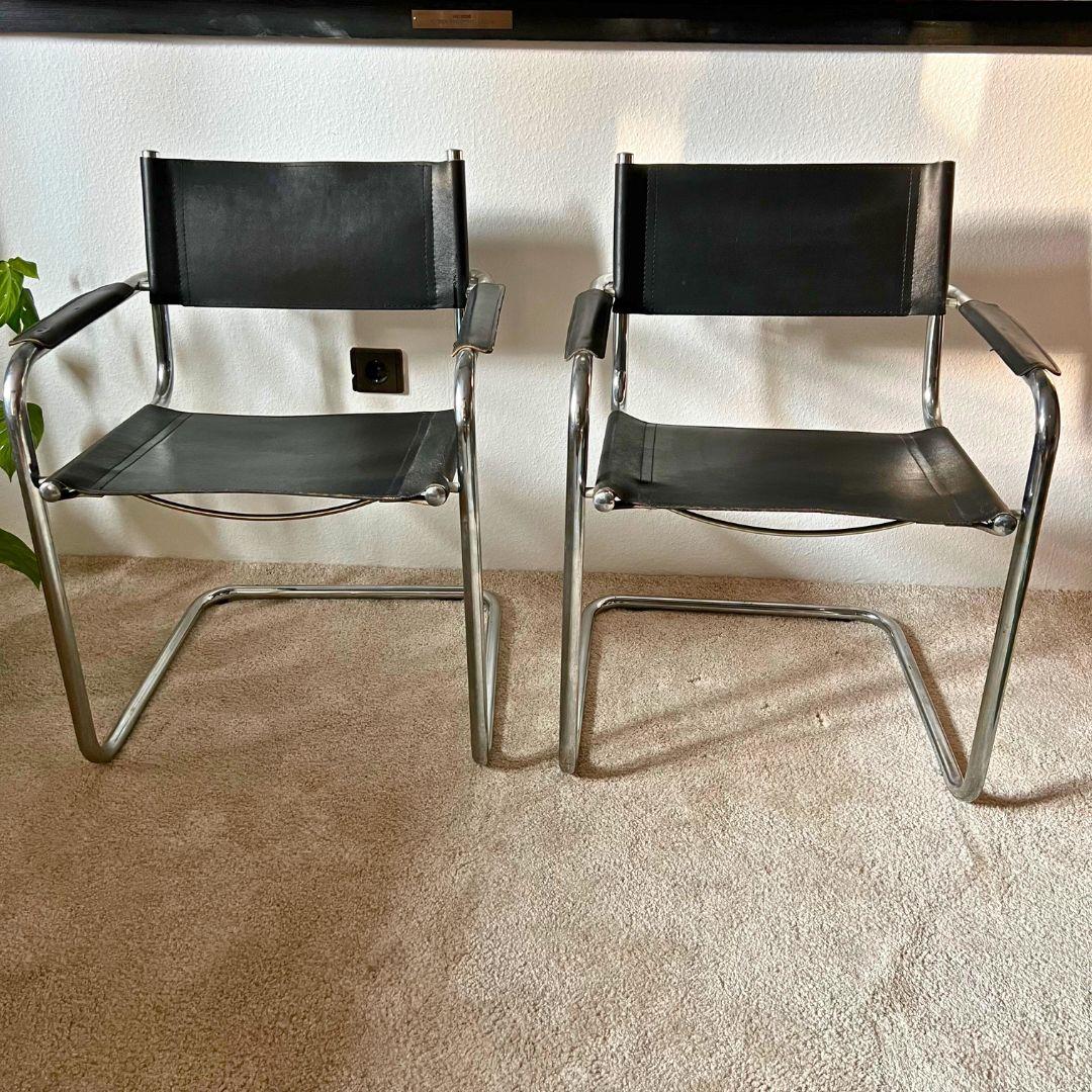 These two tubular frame armchairs were made in the style of Marcel Breuer. They are similar to the MG5 model, made of black leather and chrome tubes. Their condition is good, except for a repair on one of the armrests. Photo attached.