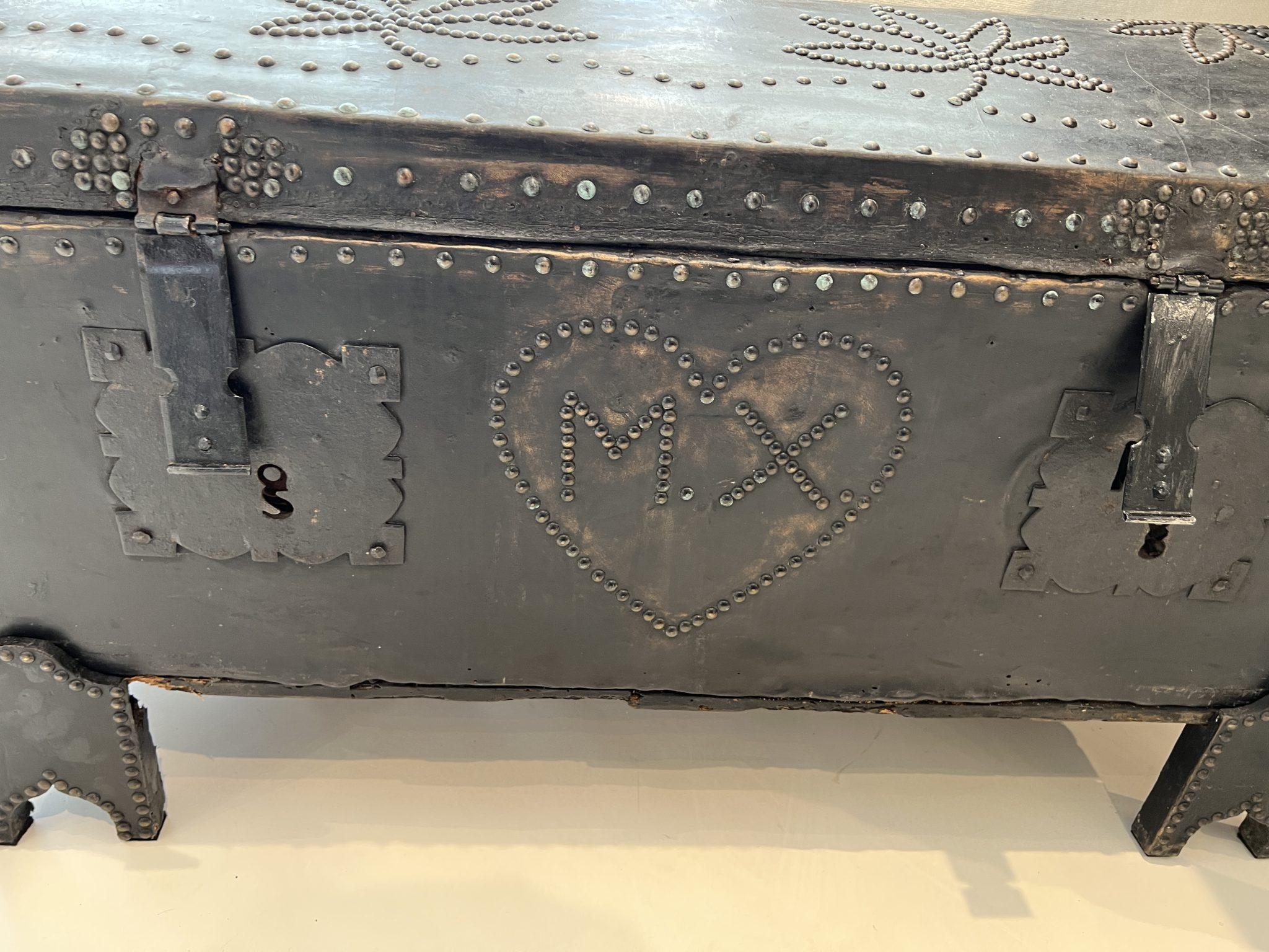 Nail heads form hearts and flowers on the top and sides of this charming leather chest on a stand.
