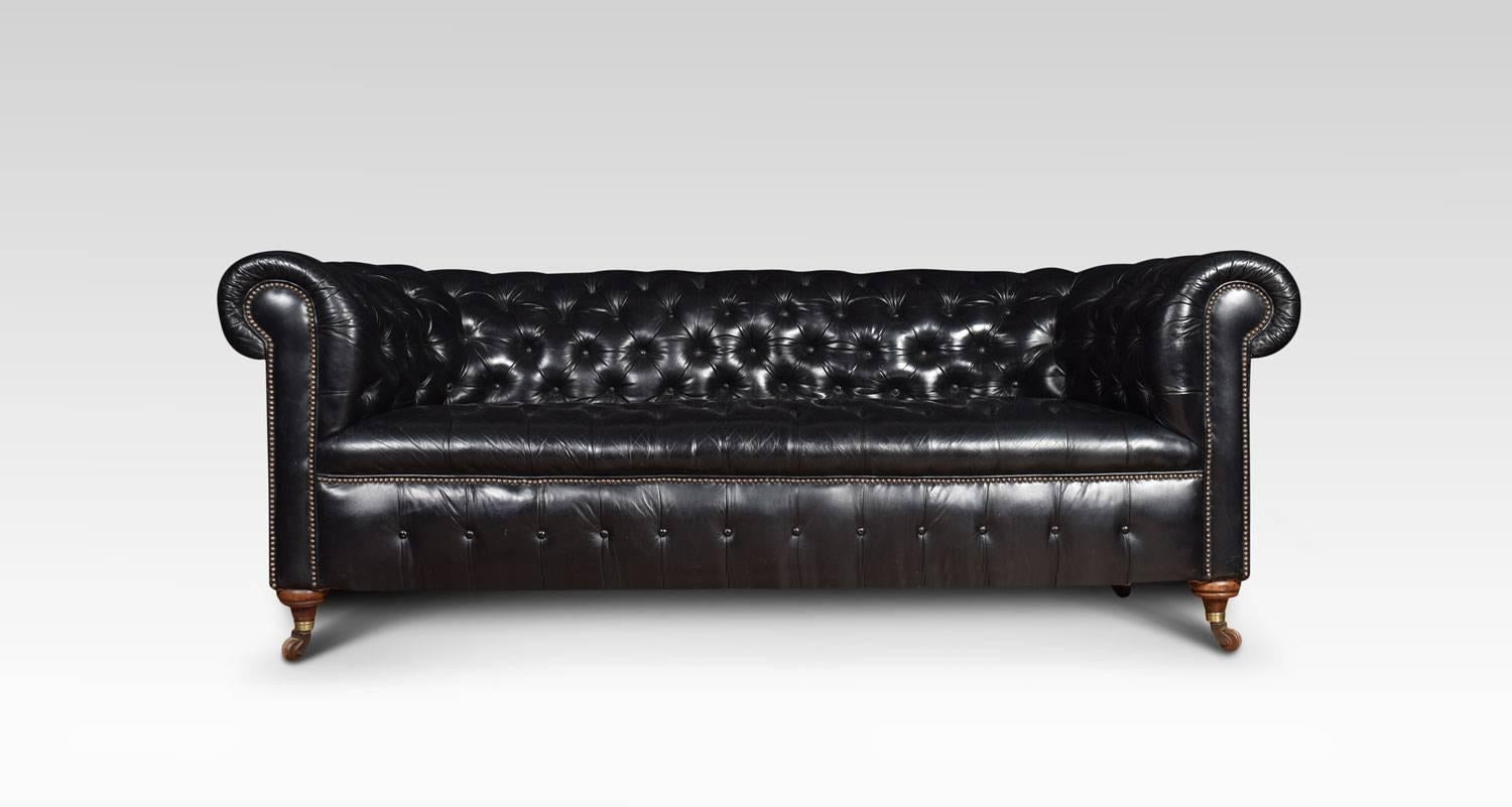 Large three-seat black leather Chesterfield sofa, having deep buttoned back and seat, raised up on turned feet with brass ceramic castors. Good solid condition, the leather is soft, nicely worn in. Dimensions:
Height 31.5 inches, Height to seat