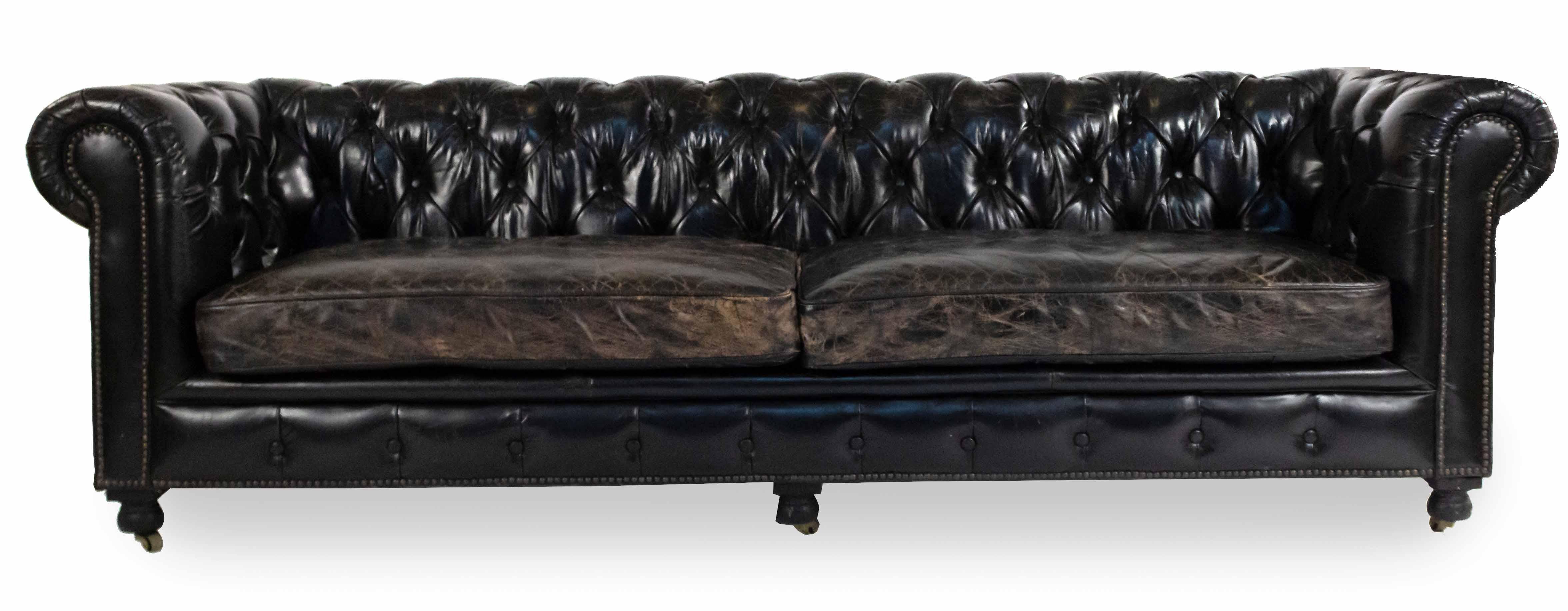 English Victorian style blackish brown tufted leather chesterfield sofa with distressed finish having out-scrolled arms with brass hail head trim & 2 seat cushions on wooden bun feet with casters and having brass hail head trim.
  
