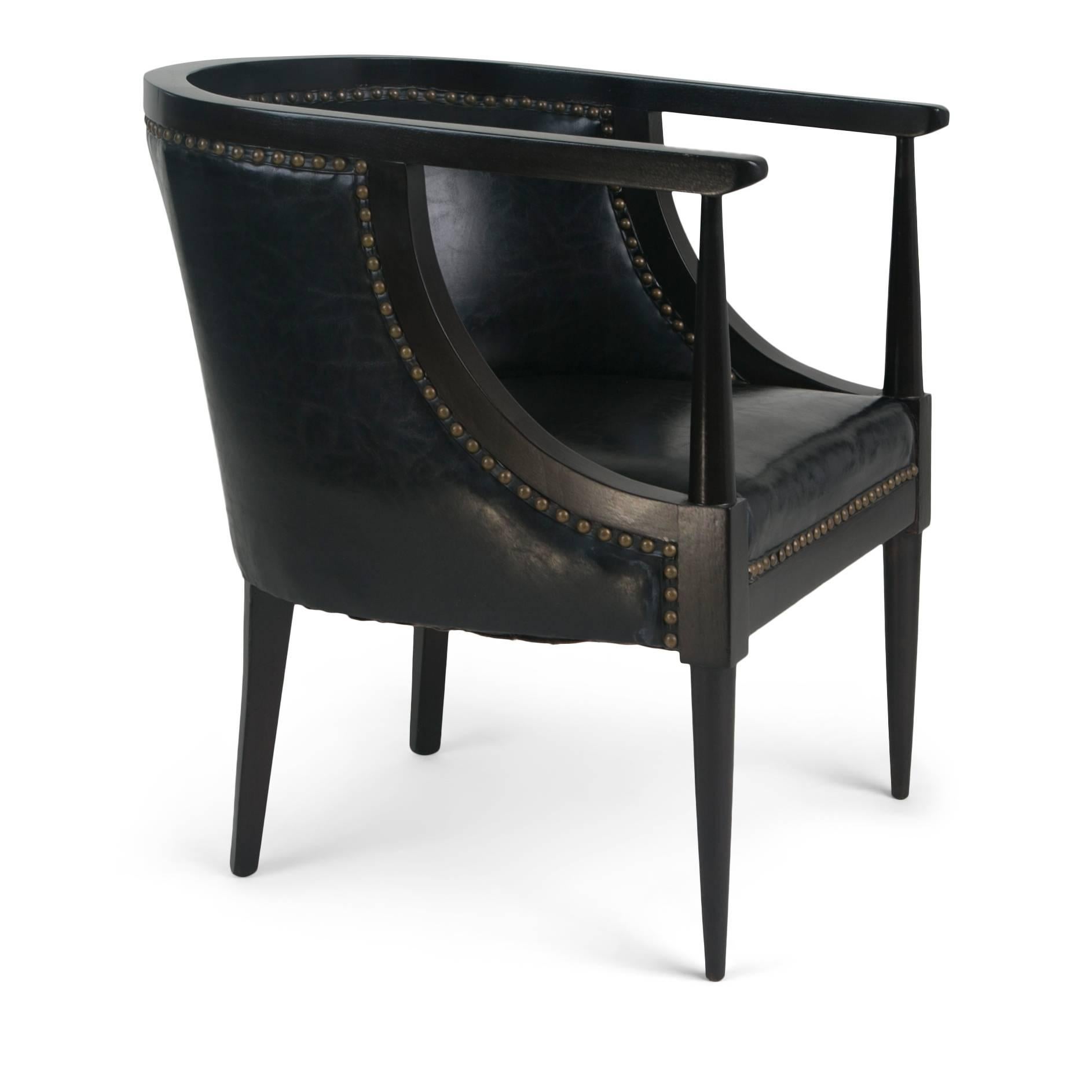 Pair of handsome Art Deco style tub chairs featuring a curved back and elegant frame. These armchairs have been upholstered in a high-quality black leather which is punctuated with bronze nailheads. These sculptural club chairs feature the use of