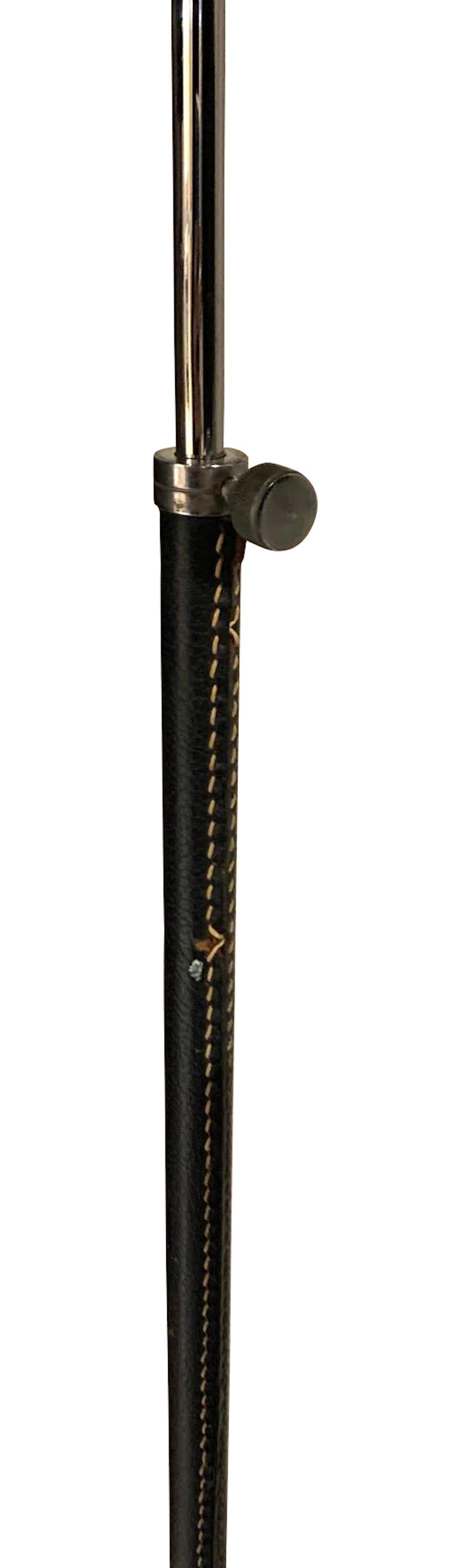 Stehlampe aus schwarzem spanischem Leder der 1960er Jahre mit naturfarbenen Kontrastnähten.
Dekorativer dreibeiniger Fuß aus Silber.
Höhe der Leuchte 47