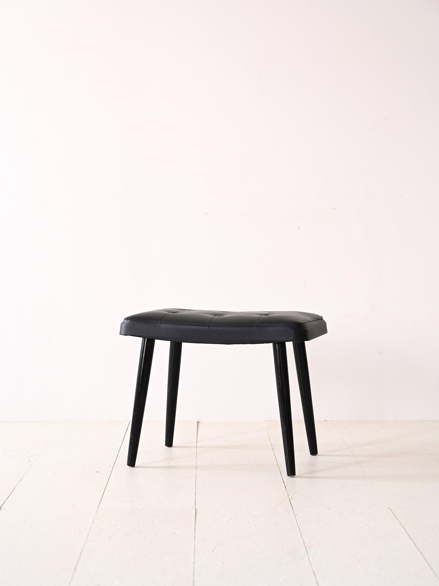 1960s Scandinavian stool.

Modern footstool consisting of a wooden base with tapered legs and an upholstered seat reupholstered with black leatherette.
The minimal and elegant lines also make it suitable for different types of interiors; it will add