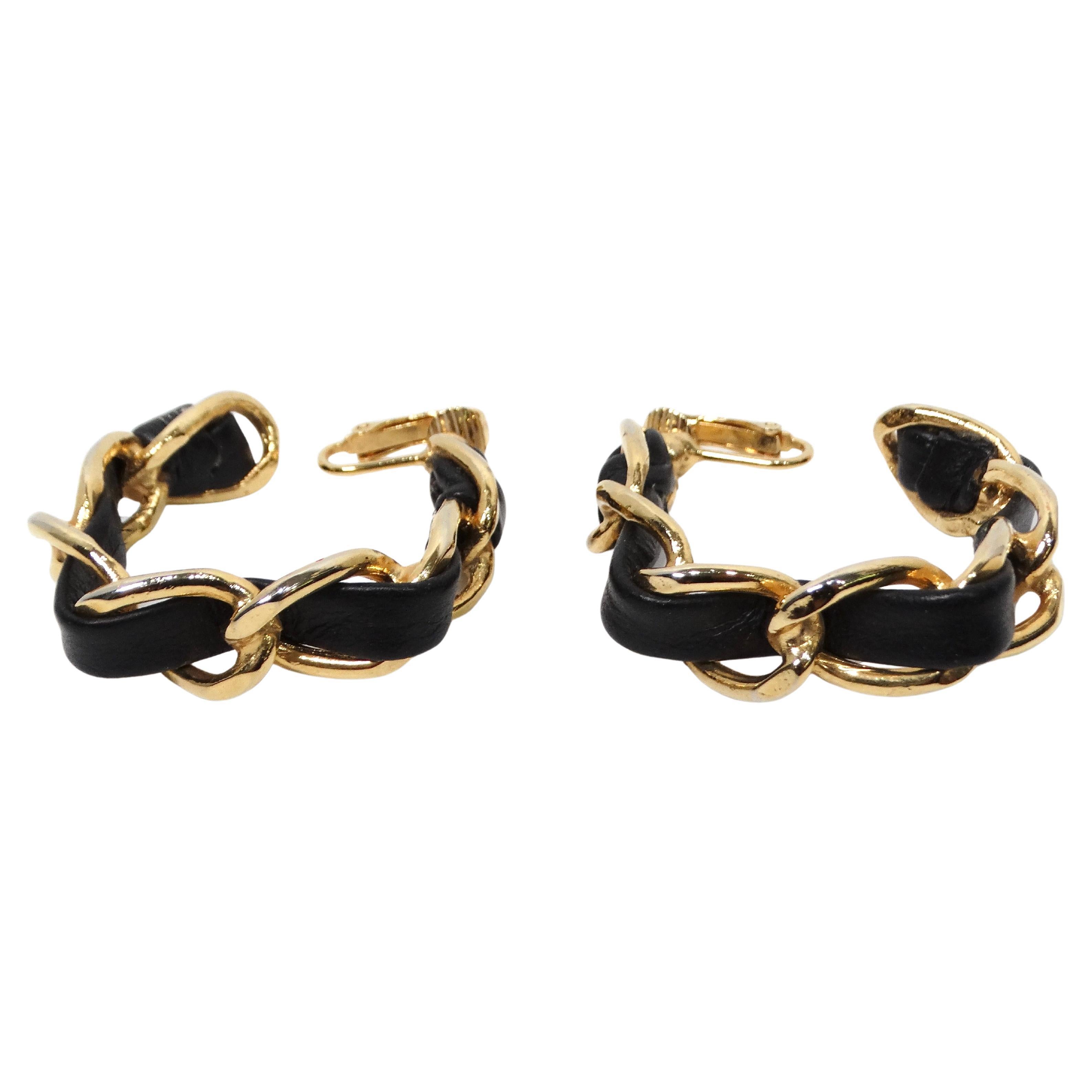Gli orecchini a cerchio quadrato in pelle nera e catena dorata degli anni '90 esemplificano lo stile audace ed eclettico caratteristico di quell'epoca. Questi straordinari orecchini sono caratterizzati da un'elegante catena in pelle nera e tonalità