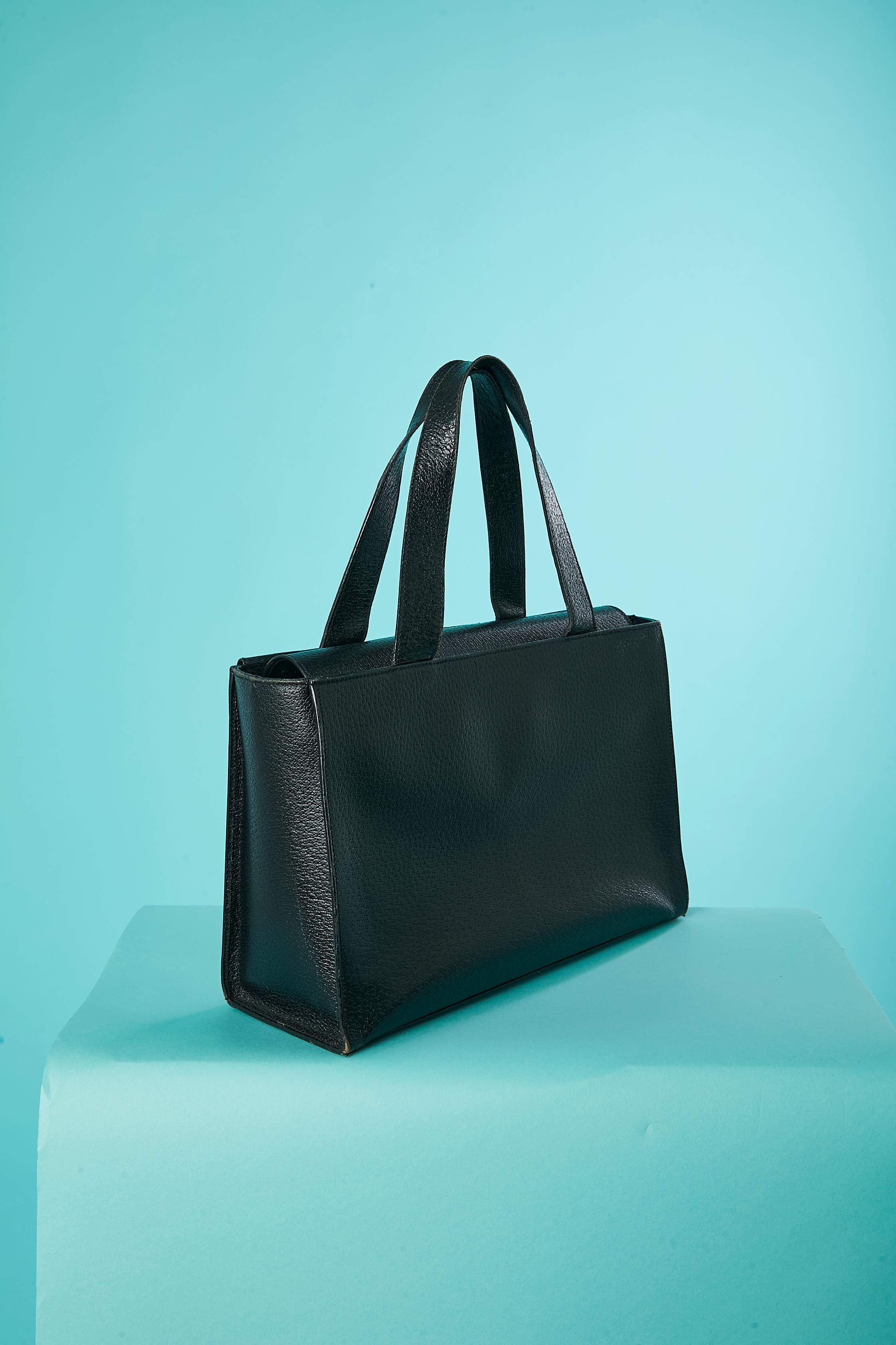 Sac à main en cuir noir avec 2 poches frontales avec fermeture à pression.  Doublure en tissu noir. Fermeture à bouton-pression sur le dessus. 2 poches à l'intérieur ( une avec fermeture éclair, une sans) ' clous en métal doré en dessous. 
TAILLE 19