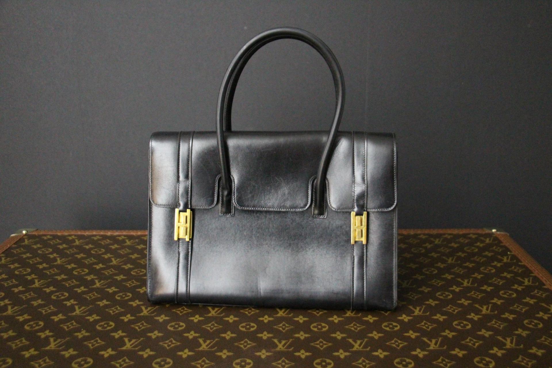 This Hermes Drag bag features black calfskin leather with its two golden plated H-closure buckles .Its double leather handles offer both comfort and style .It rests on 4 little brass studs. It is stamped Hermes Paris under its flap in golden