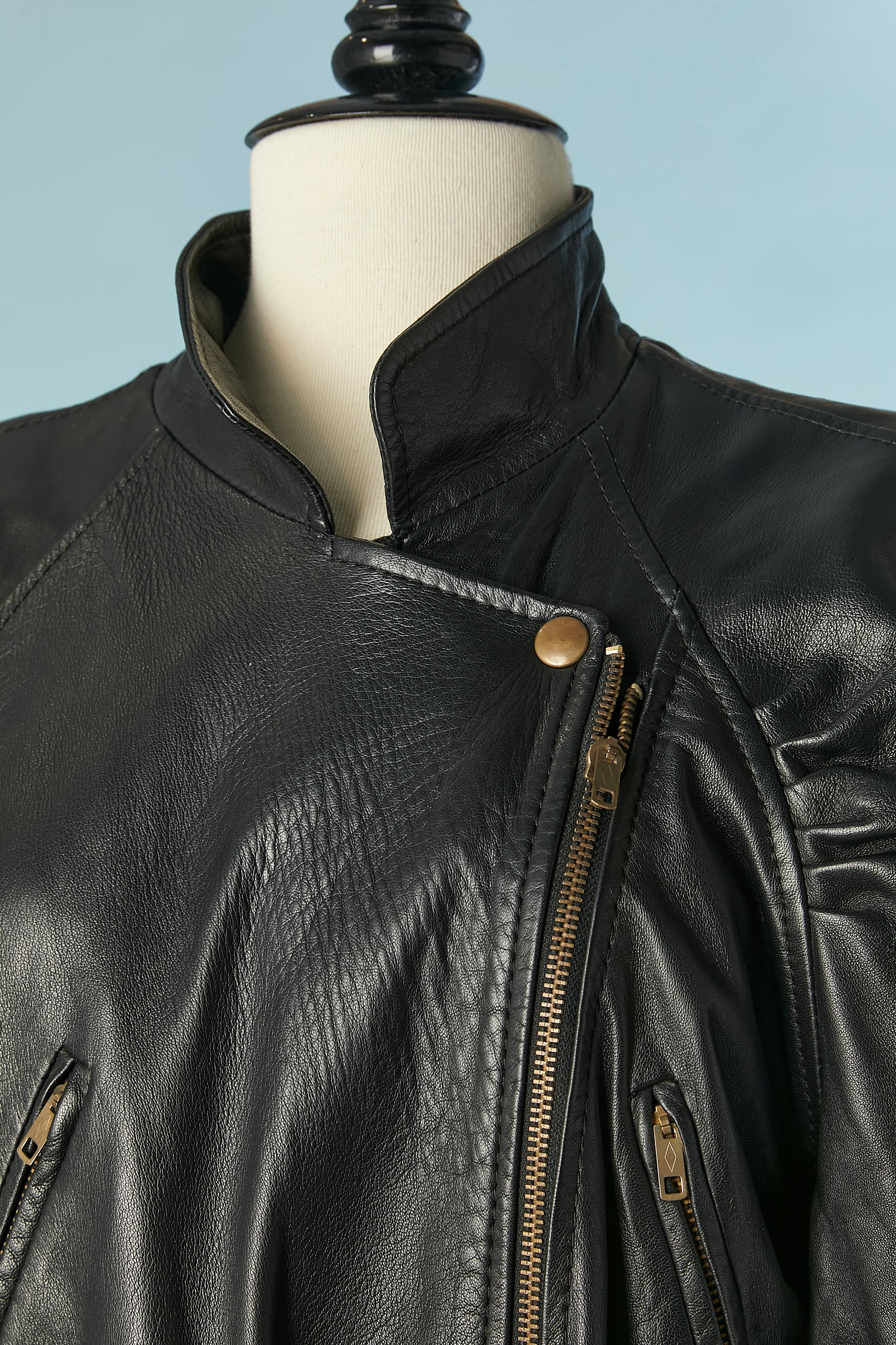 Black leather jumpsuit . Shoulder-pad. Zip closure in the middle front and one snap on the top . 4 pockets in the front ( 2 are closed with a zip) and one pocket on the back ( with zip closure) 
Draped along the shoulder line. Raw -cut bottom edge.