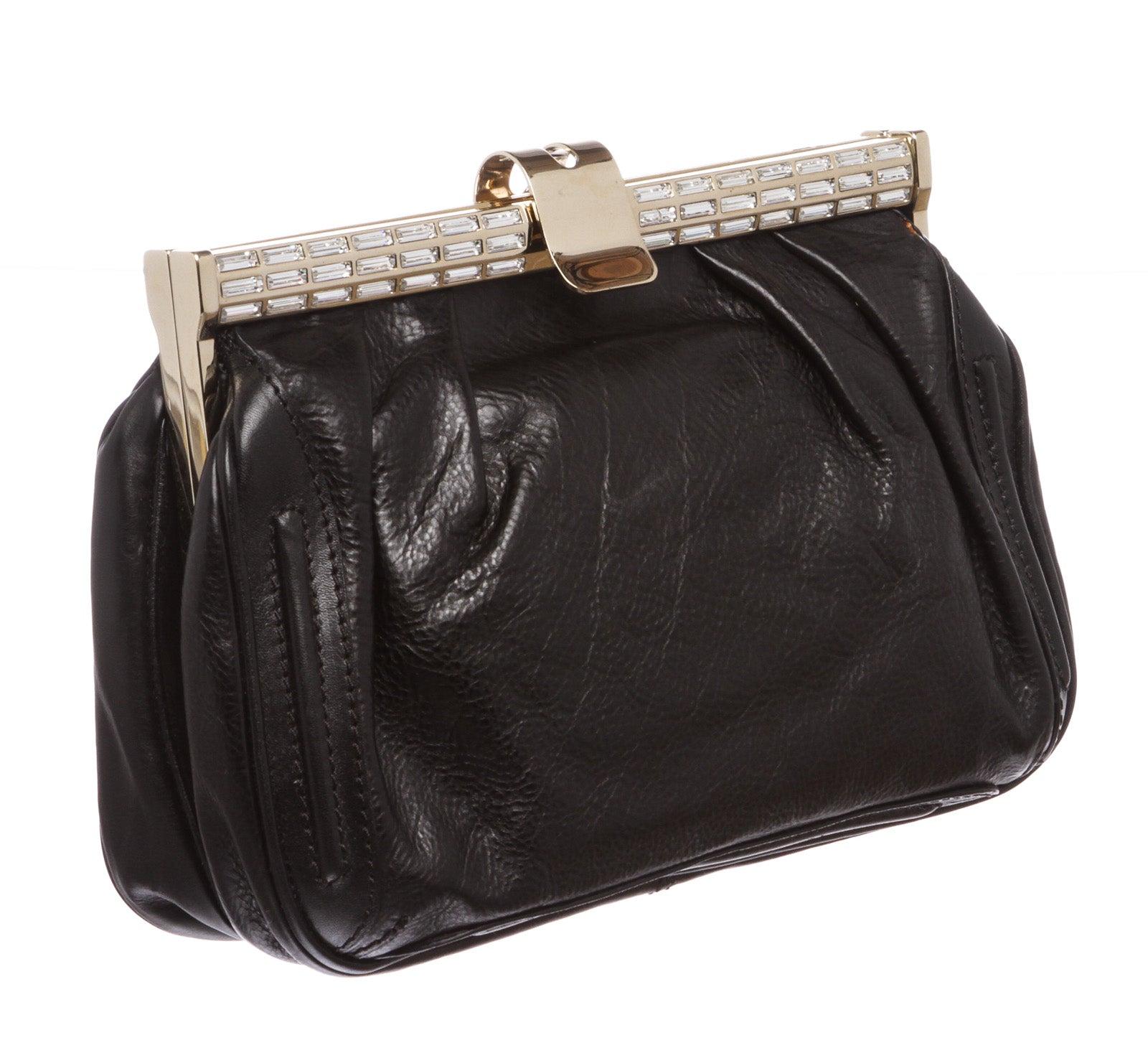 Black leather MCM clutch with gold-tone hardware and small crystal embellishments at top. Interior contains black satin lining with one slip pocket and one zipper pocket at interior wall and push-lock closure at top. Includes removable chain