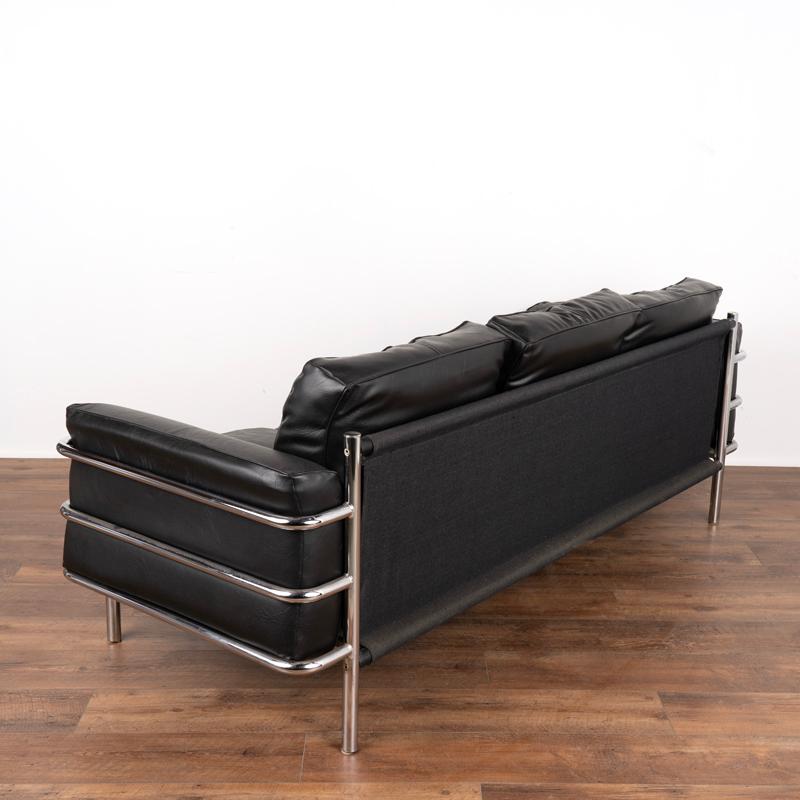 This handsome mid century modern sofa has both a modern and timeless appeal due to the classic black leather and chrome frame. The front reflects the look of a Le Corbusier LC3 sofa but was made in Denmark with a simple fabric back. It is 6.5' long