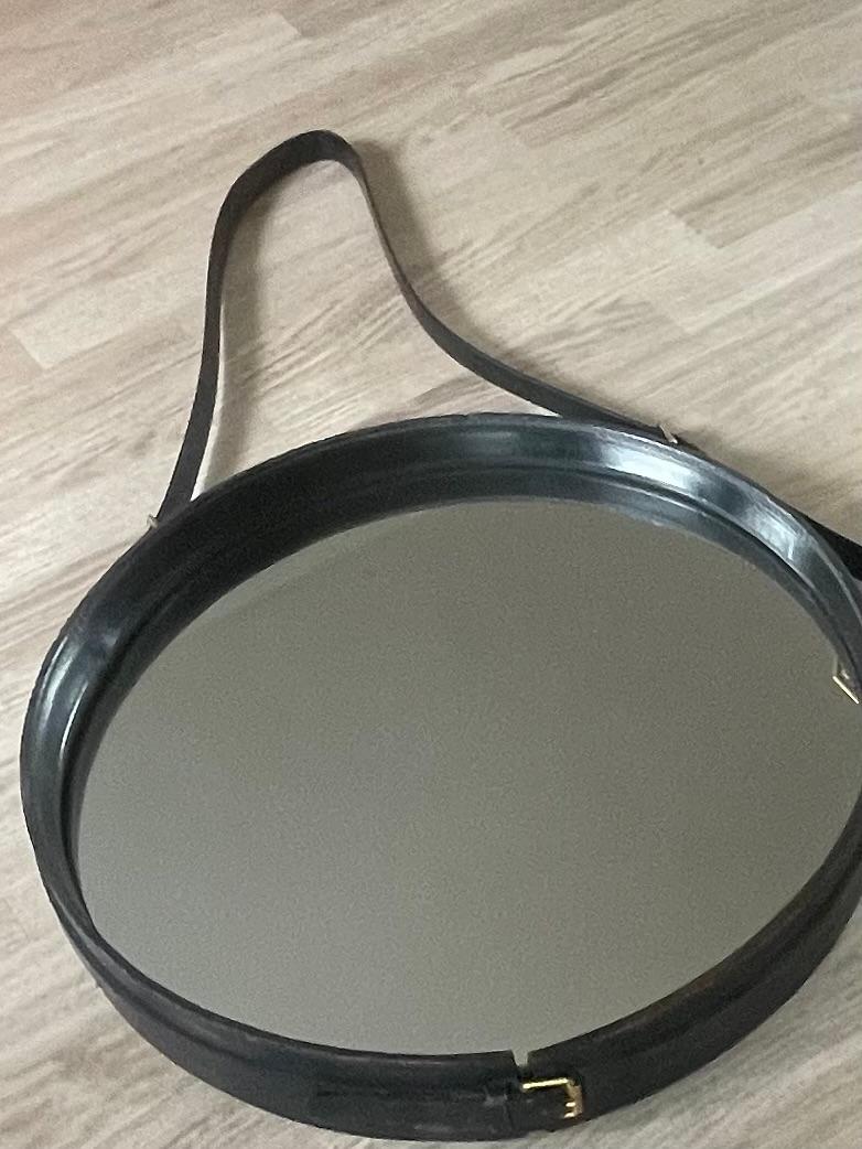 V.intage circular mirror covered with black leather by Maison 
Hermes.
Leather straps with brass buckels.
Original piece from the fifties designed by Jacques Adnet.
France 1950.