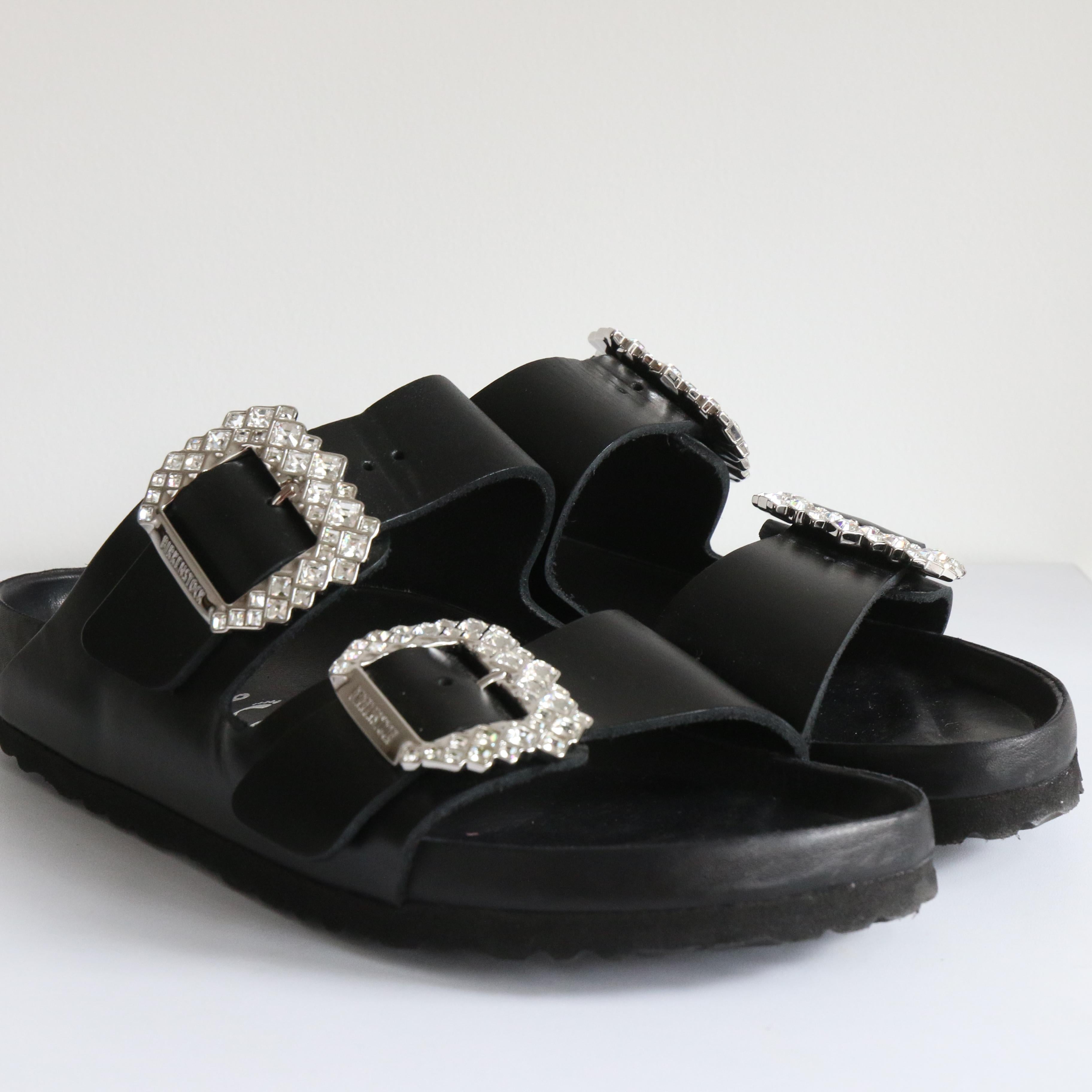 This sparkling pair of Birkenstock sandals from the highly sought after and now sold out 2022 capsule collection with Manolo Blahnik are the perfect summer shoe. 

In soft black leather with an an open toe, and statement double buckle design, with