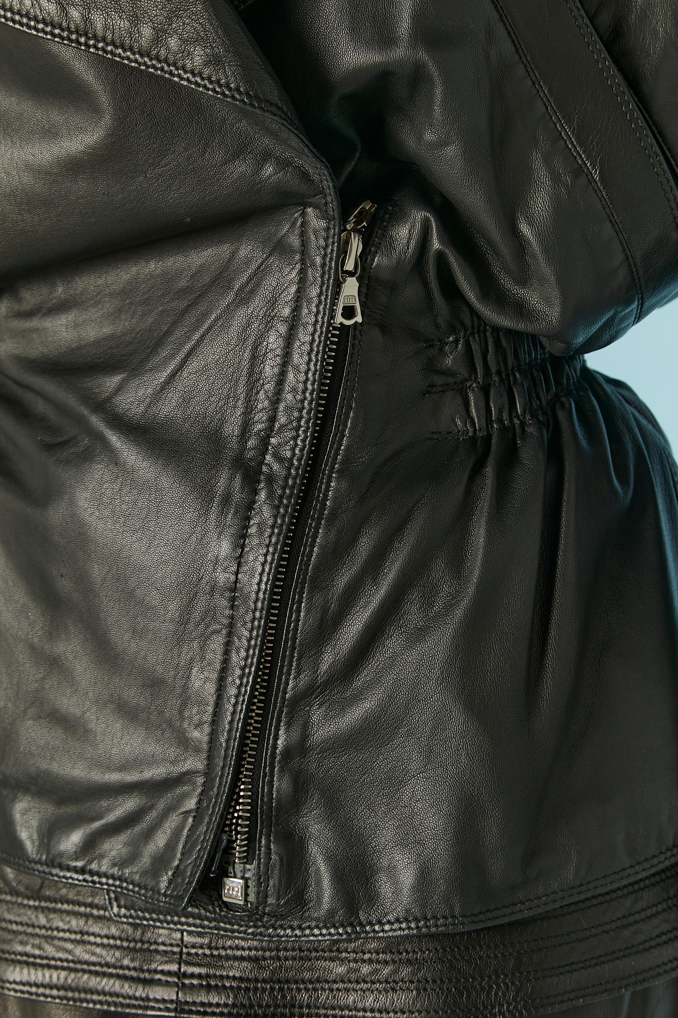 Black lambskin leather skirt-suit. Shoulder pad. The fabric composition tag has been cut but the lining is probably in rayon. Zip pocket on the collar and one on the left side. Elastic waist on the back of the jacket. 
Some imperfections on the