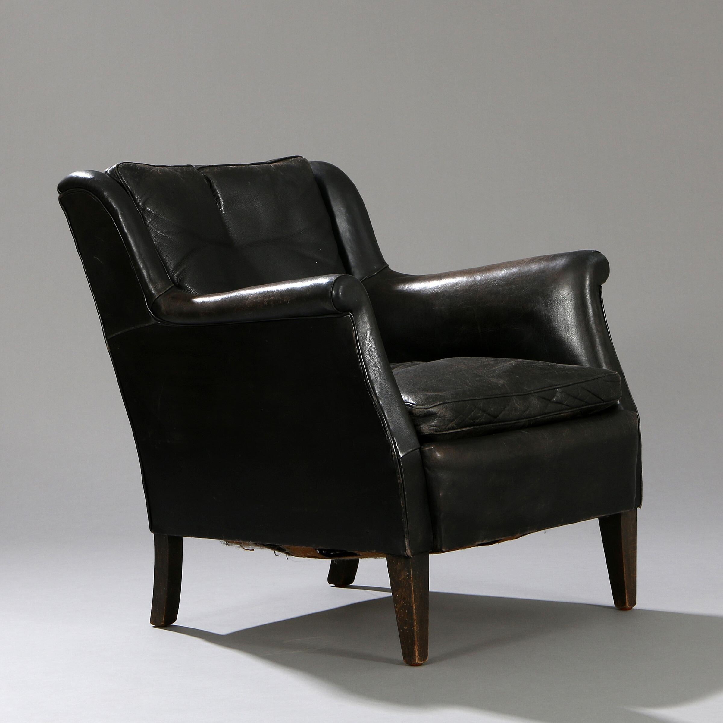 This black leather sofa and armchair were probably made by cabinetmaker Frits Henningsen, circa 1950. The original black leather is well patinated with signs of wear and some cracking to leather. The backrest reclines significantly, making this a