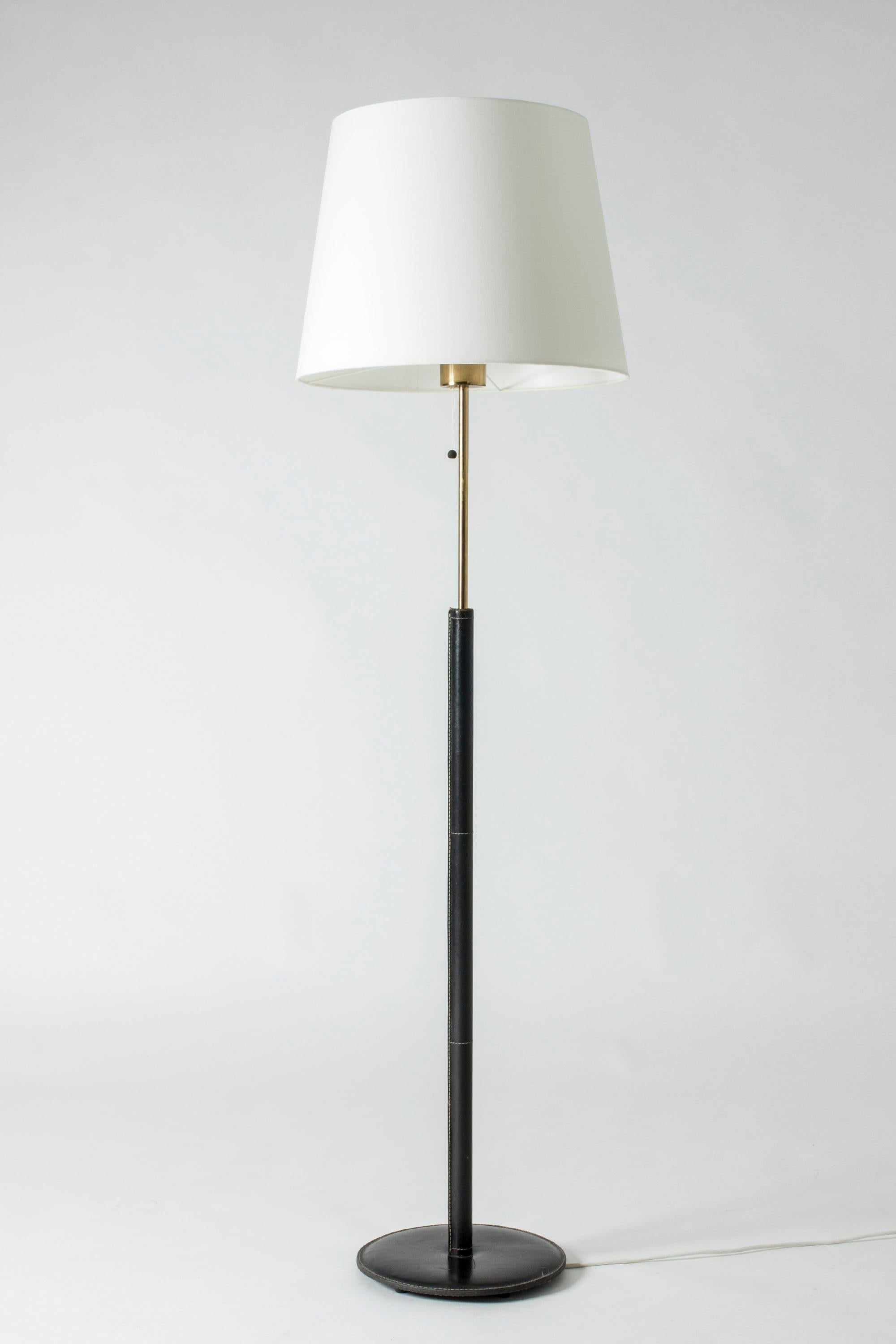 Cool floor lamp from Bergboms with a leather-clad brass pole and foot. Black leather with contrasting white seams.

Bergboms was a successful Swedish lighting firm which manufactured both own designs and those of international designers such as