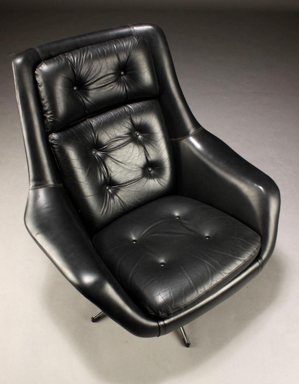 Swivel armchair designed by Henry Walter Klein for Bramin, Denmark. Upholstered with button tufted black leather, frame of stainless steel. There is a small cut on the right armrest, shown on photos.