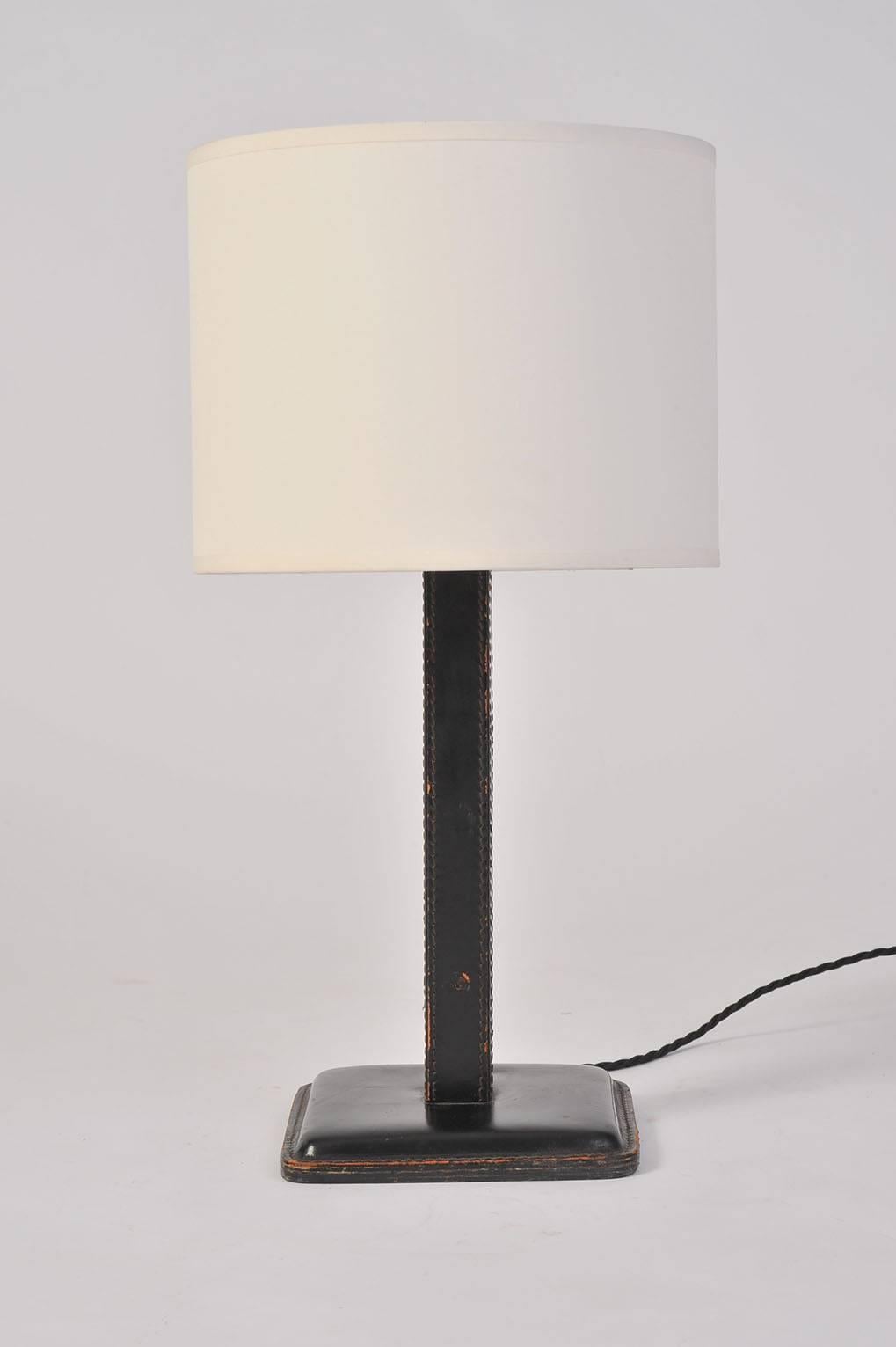 A saddle stitched black leather table lamp, with its original push switch to the base
France, circa 1930.