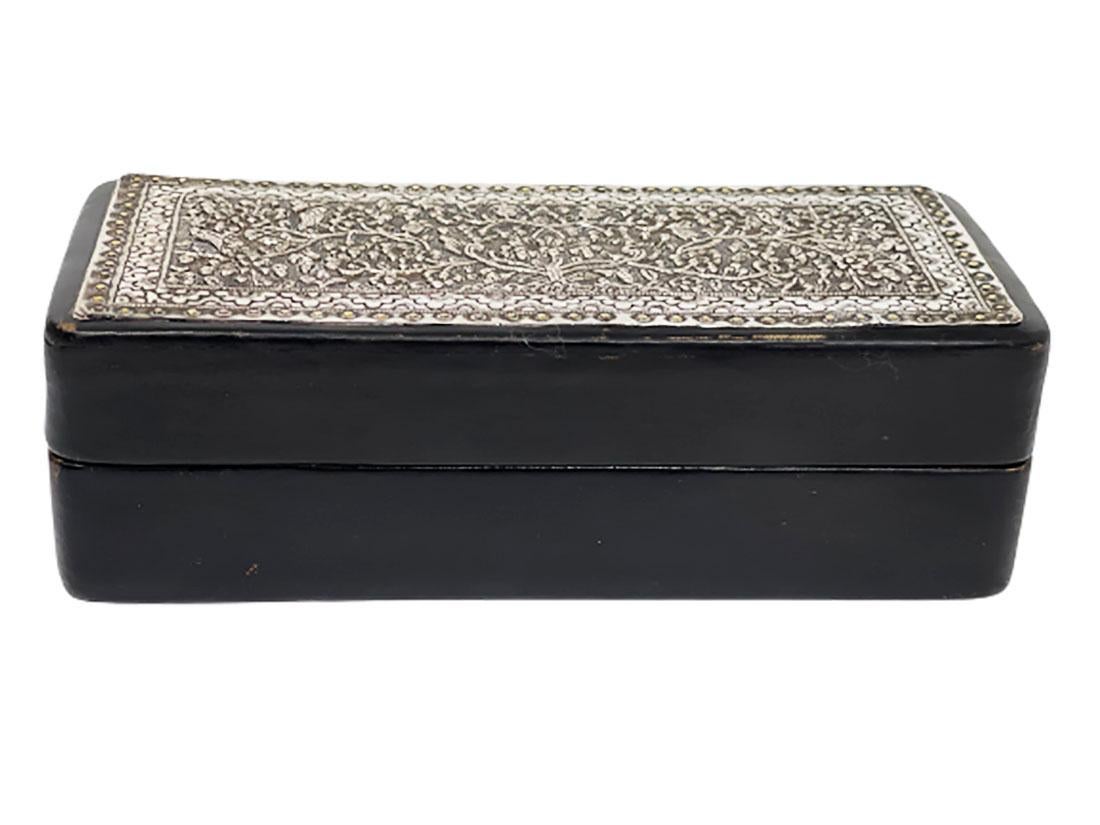 Black leather with Indonesian silver 1920s box

A rectangular box in black leather with Indonesian silver on top of the lid 
The interior is with wood
The silver handmade thin plate has a richly floral and birds motif
The measurements are 6 cm