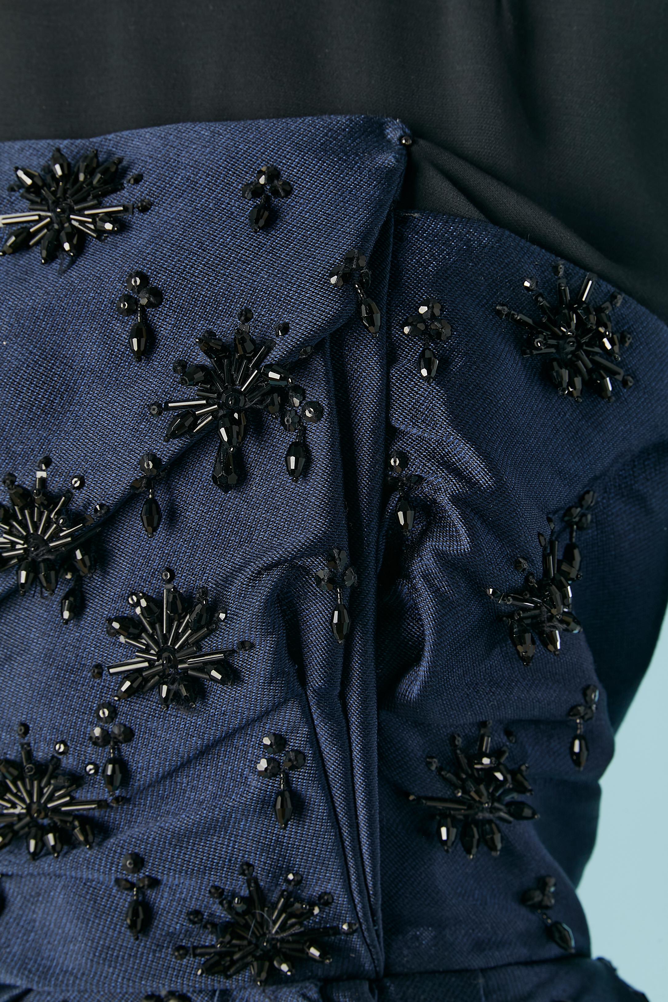 Tee-shirt noir à manches longues en rayonne avec bustier drapé en serge et perles bleues. Manches raglan. Fermeture à glissière cachée au milieu du dos et bouton-pression. 
Design/One par Bill Gaytten. 
Show piece / FW 2012
TAILLE 38 (Fr) M 