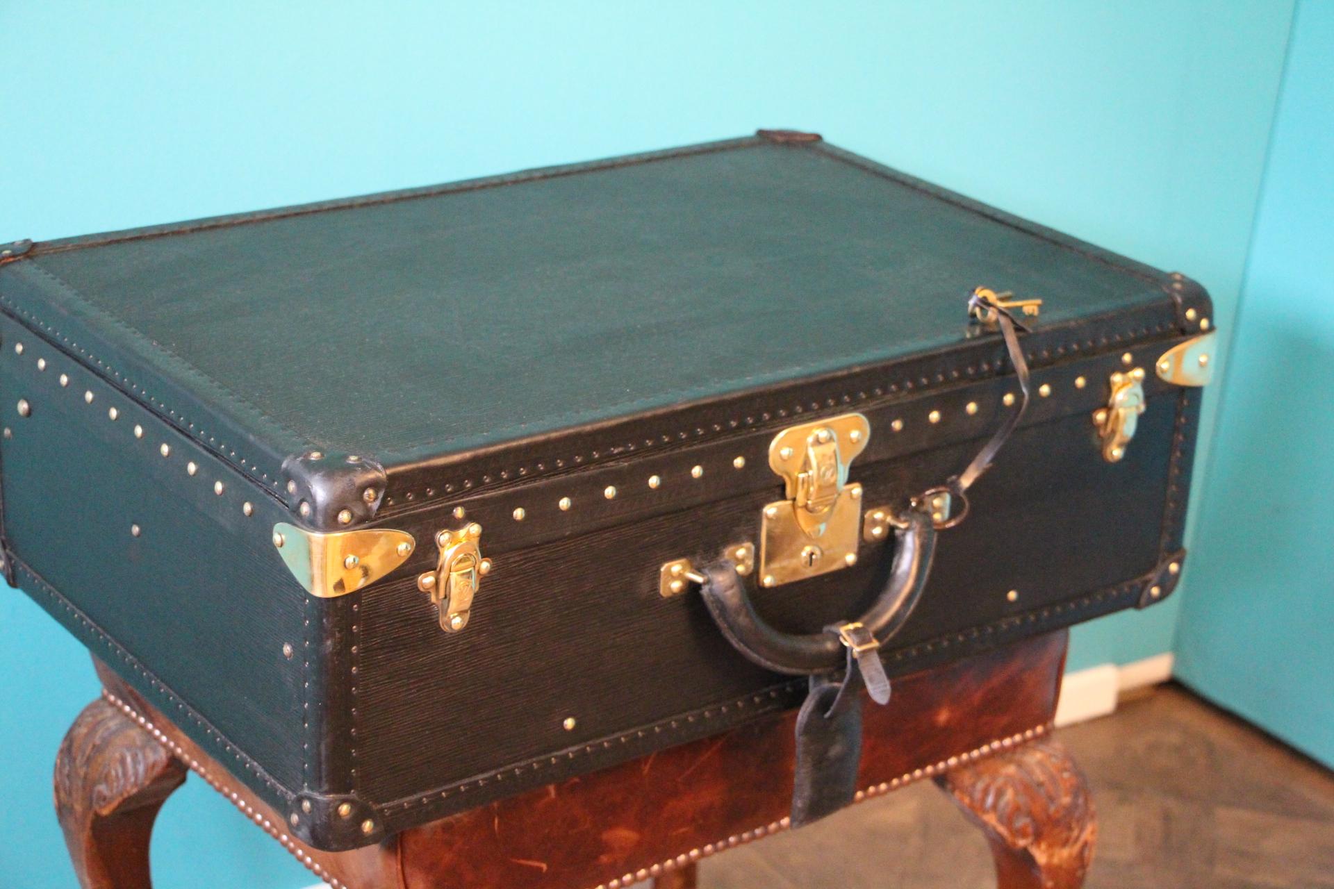 This top of the range all black leather Alzer 65 rigid suitcase features black leather trim, all solid brass LV stamped lock, clasps and studs. Large leather handle.
1 matching black epi leather name holder.
Its interior is in excellent condition,