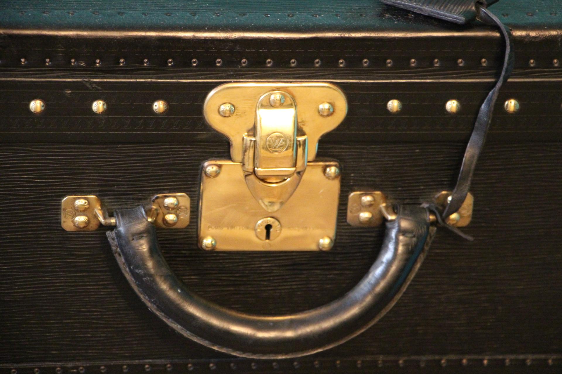 This top of the range all black leather Alzer 80 rigid suitcase features black leather trim, all solid brass LV stamped lock, clasps and studs. Large leather handle. 2 keys.
Its interior is in excellent condition, as new. It is lined in grey suede,