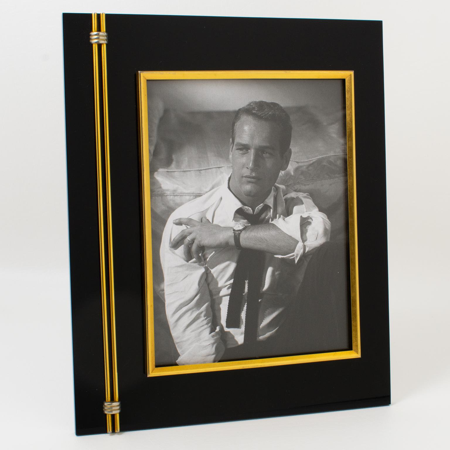 This elegant modernist picture photo frame was crafted in Italy in the 1970s. The refined minimalist design boasts a thick black Lucite slab with a gilded brass decor accent. The easel at the back is chromed metal. The frame can be placed in a