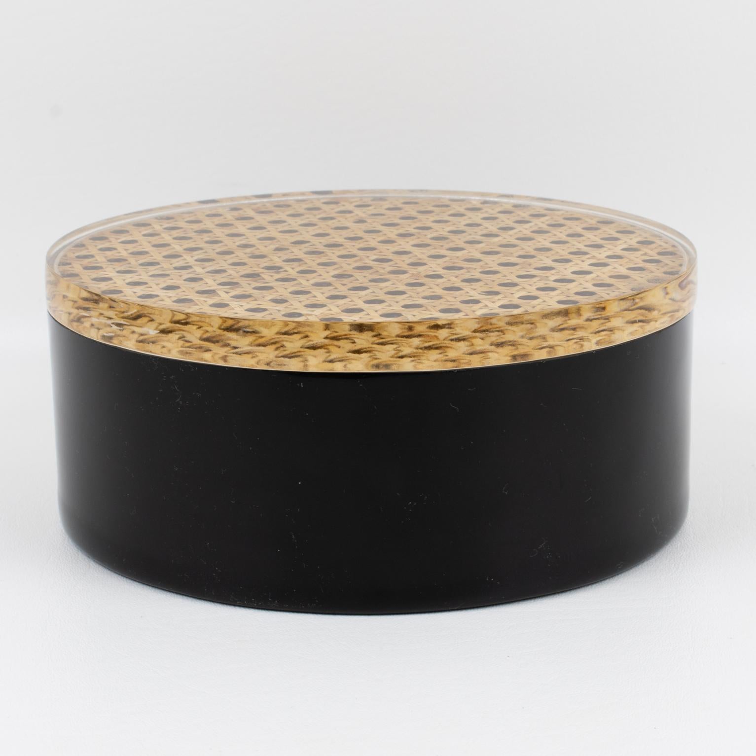 This decorative Italian Lucite lidded box was crafted in the 1970s. The piece boasts a rounded shape with a base in true licorice black Lucite topped with a lid in crystal clear Lucite with natural rattan, wicker, or cane work embedded in the