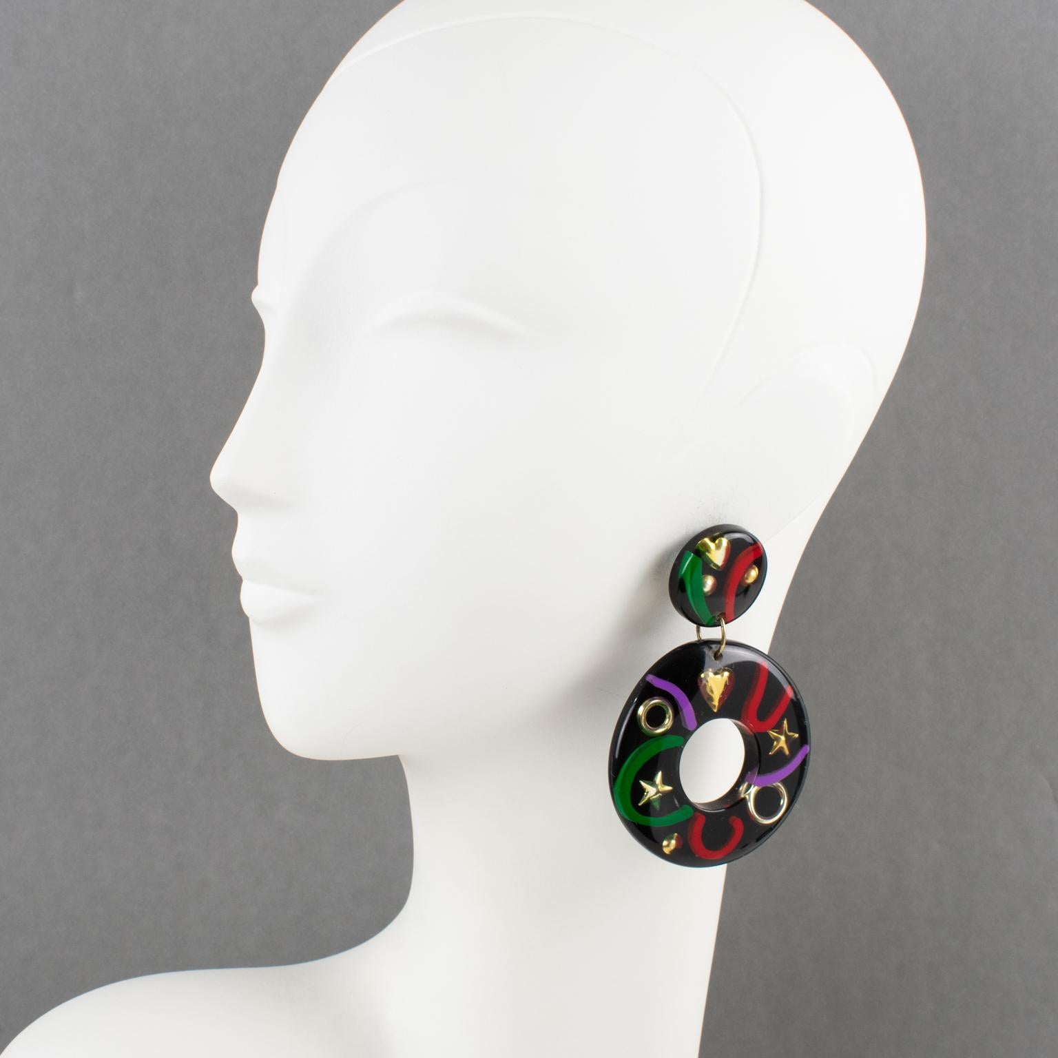 These lovely Lucite or Resin dangling clip-on earrings were made in Italy. They feature an oversized donut shape in true licorice black color with gilded heart, star, and ring inclusions, complimented with green, purple, and red 