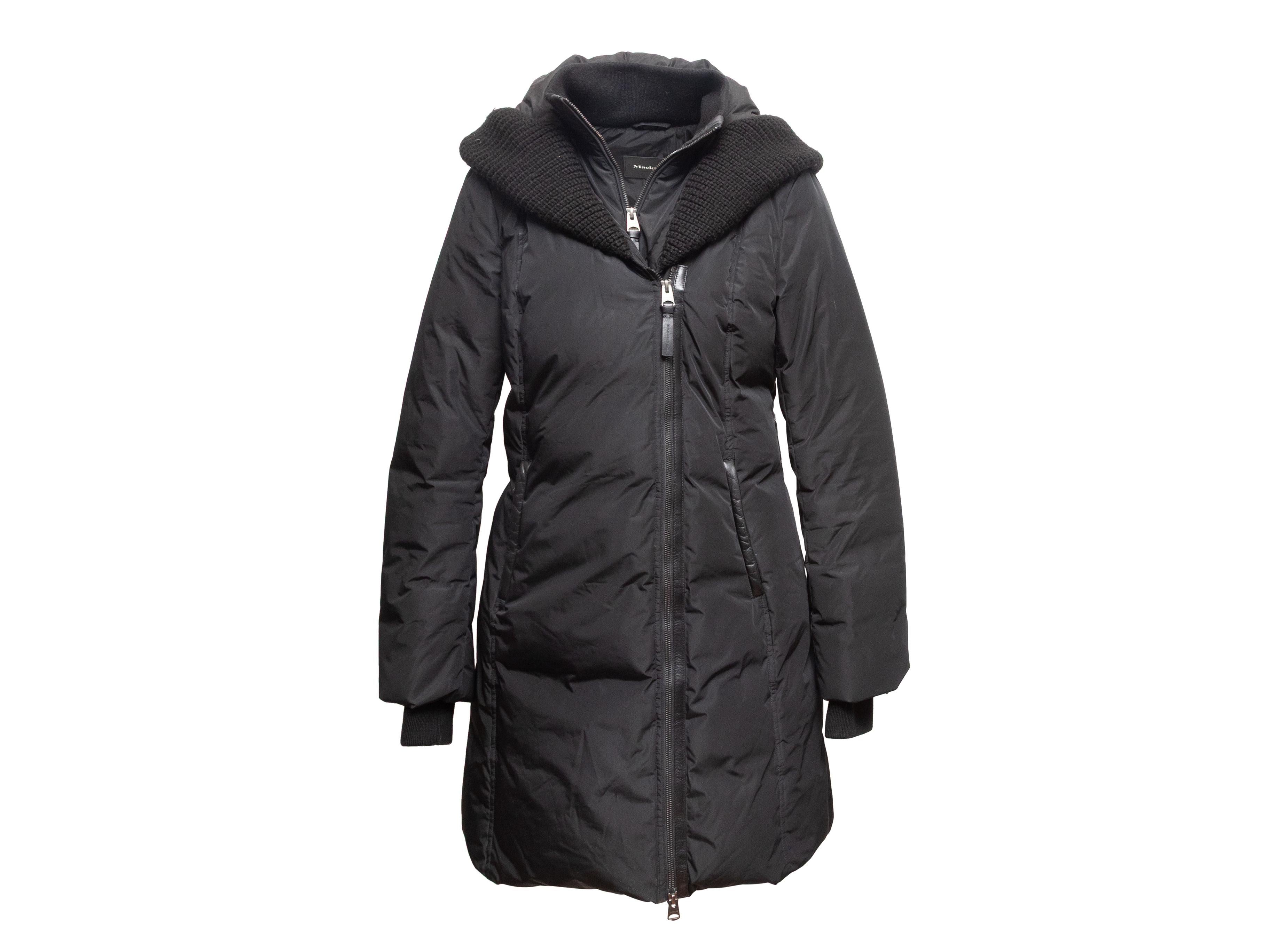 Manteau noir à capuche en duvet de Mackage. Bordure en tricot côtelé. Deux poches sur les hanches. Fermeture à glissière sur le devant. Poitrine 38