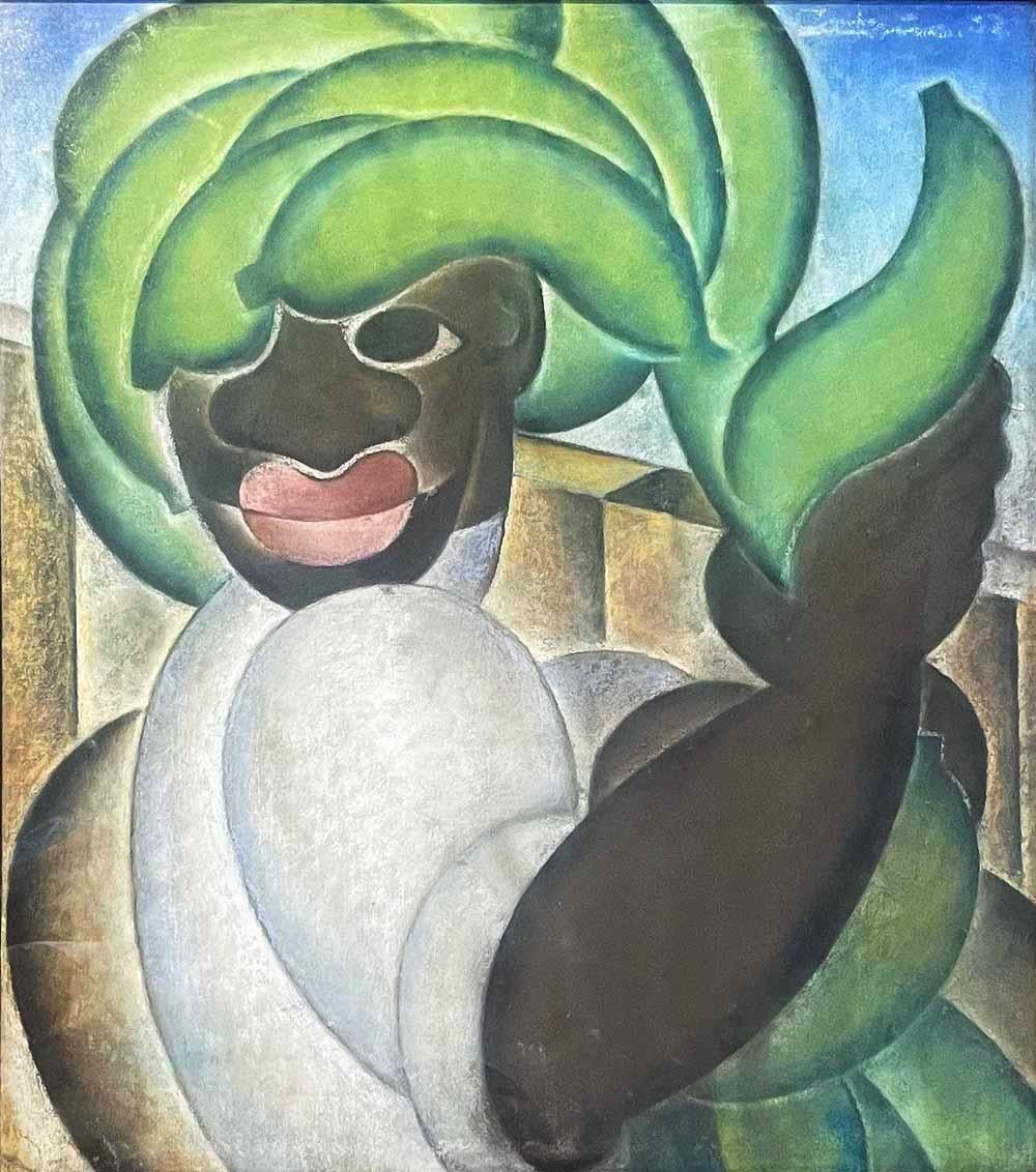 Executed in a brilliant palette of sky blue, jade green, ivory and chocolate brown, this striking drawing of a Black male figure carrying a pile of green bananas on his head was done in pastels on paper.  The figure, his load of green fruit and his