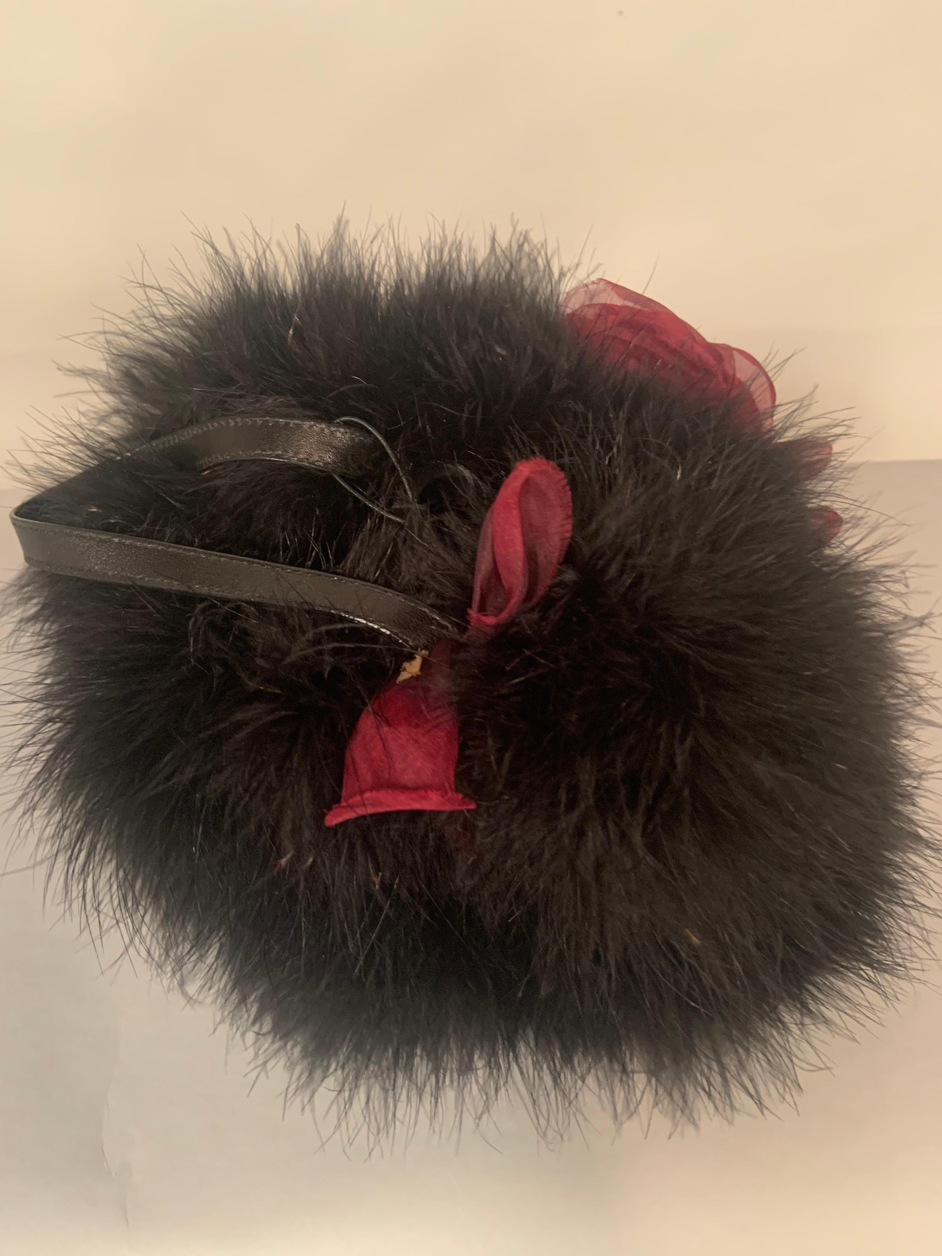 This witty Italian handbag from Desmo is crafted from marabou feathers, lined with silk chiffon and trimmed with two large claret colored roses. The bag has a black leather strap handle and an oval black leather bottom.  It has never been used,
