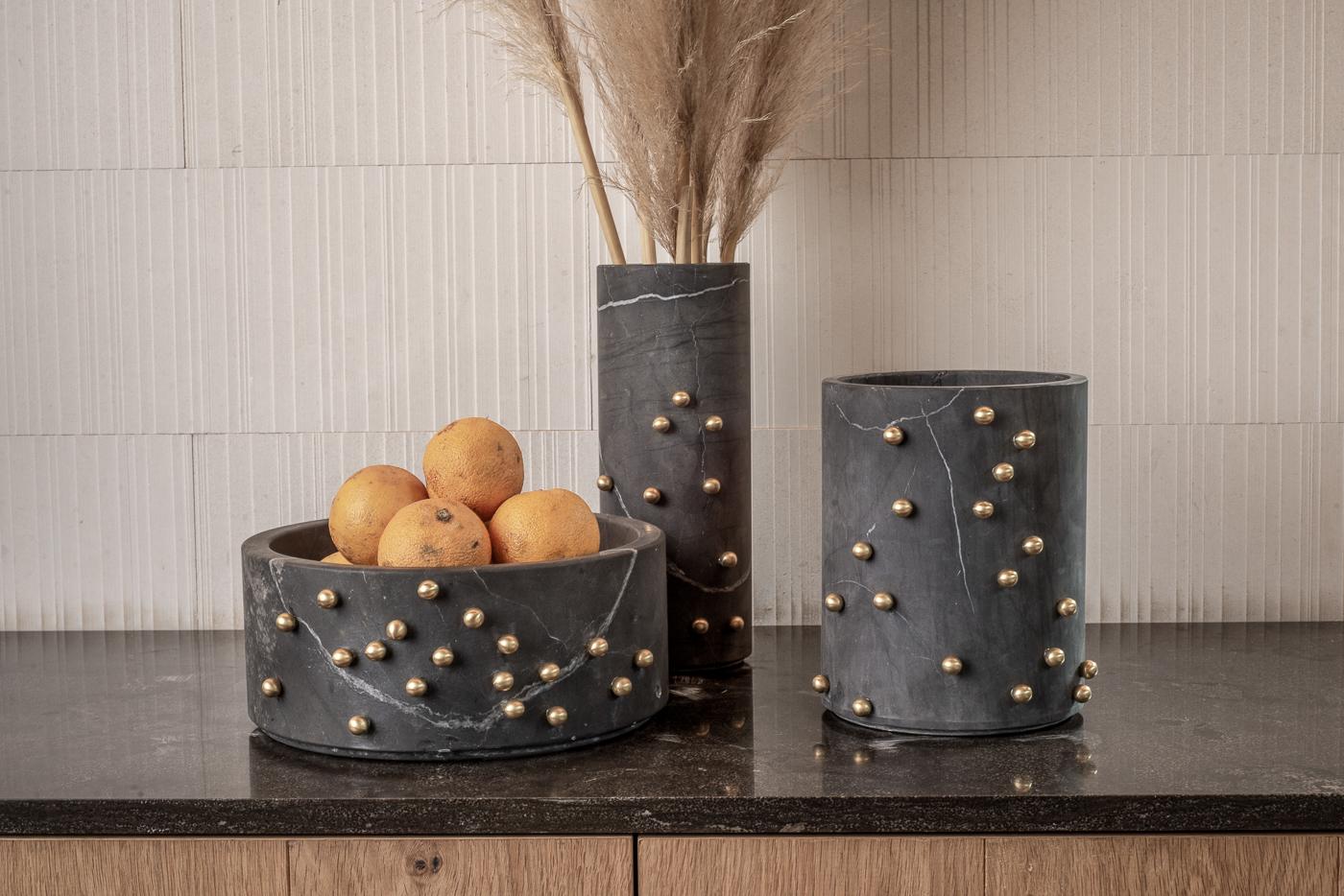 Elevate your decor with our exquisite cylindrical bowl adorned with lustrous brass sprinkles that seem to dance at random intervals along its sides. This elegant and daring bowl is a showstopper on any set, whether it's holding a vibrant bouquet of